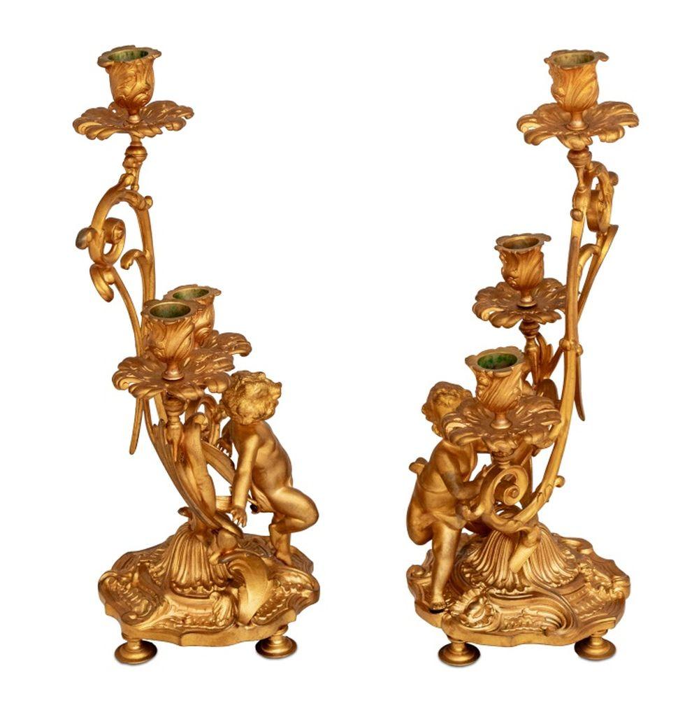Pareja de candelabros figurados de metal dorado estilo Luis XV, finales del siglo XIX, cada uno ricamente dorado, con tres luces en volutas sostenidas por un querubín drapeado, sobre base lobulada, con cuatro pies. 14,5