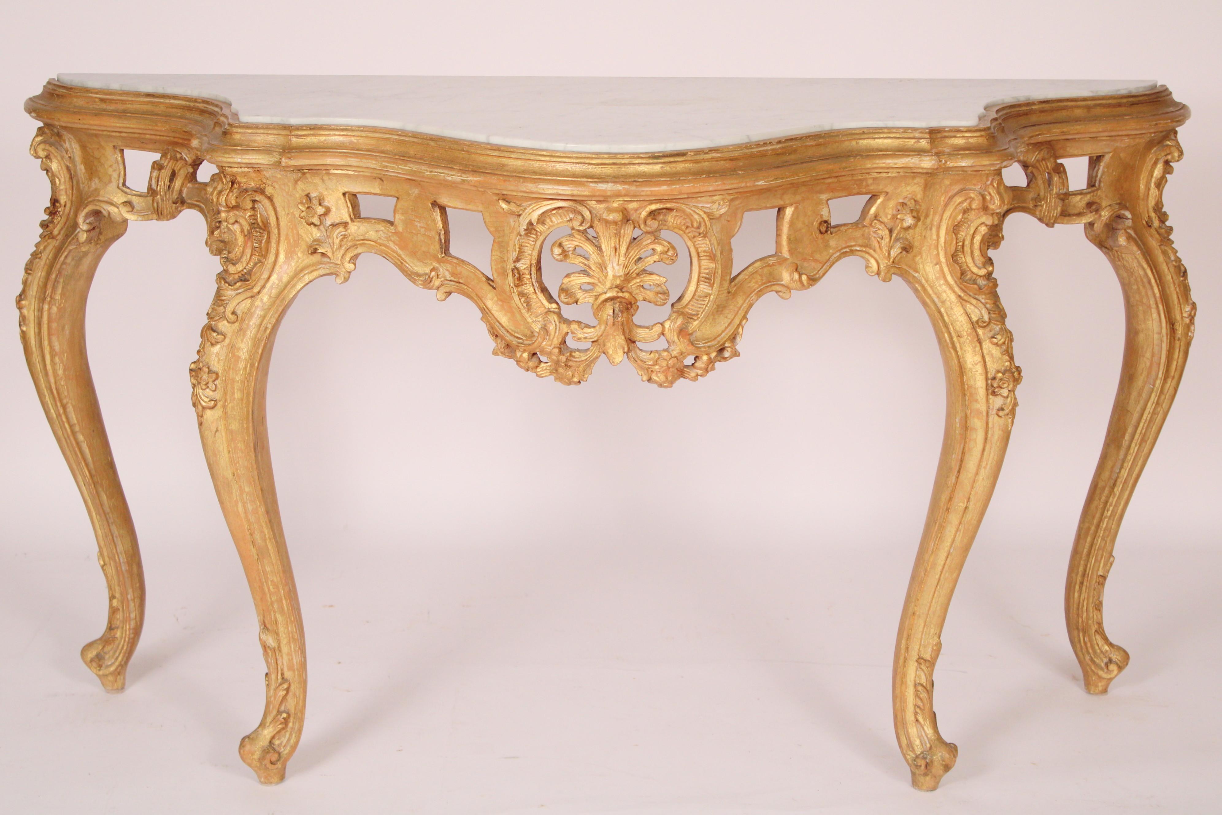 Louis XV style carved gilt wood marble top console table, late 20th century. The top with an inset Carrera marble top, gilt wood frieze with central floral carving, resting on cabriole legs ending in French fiddle feet. The finish is intentionally