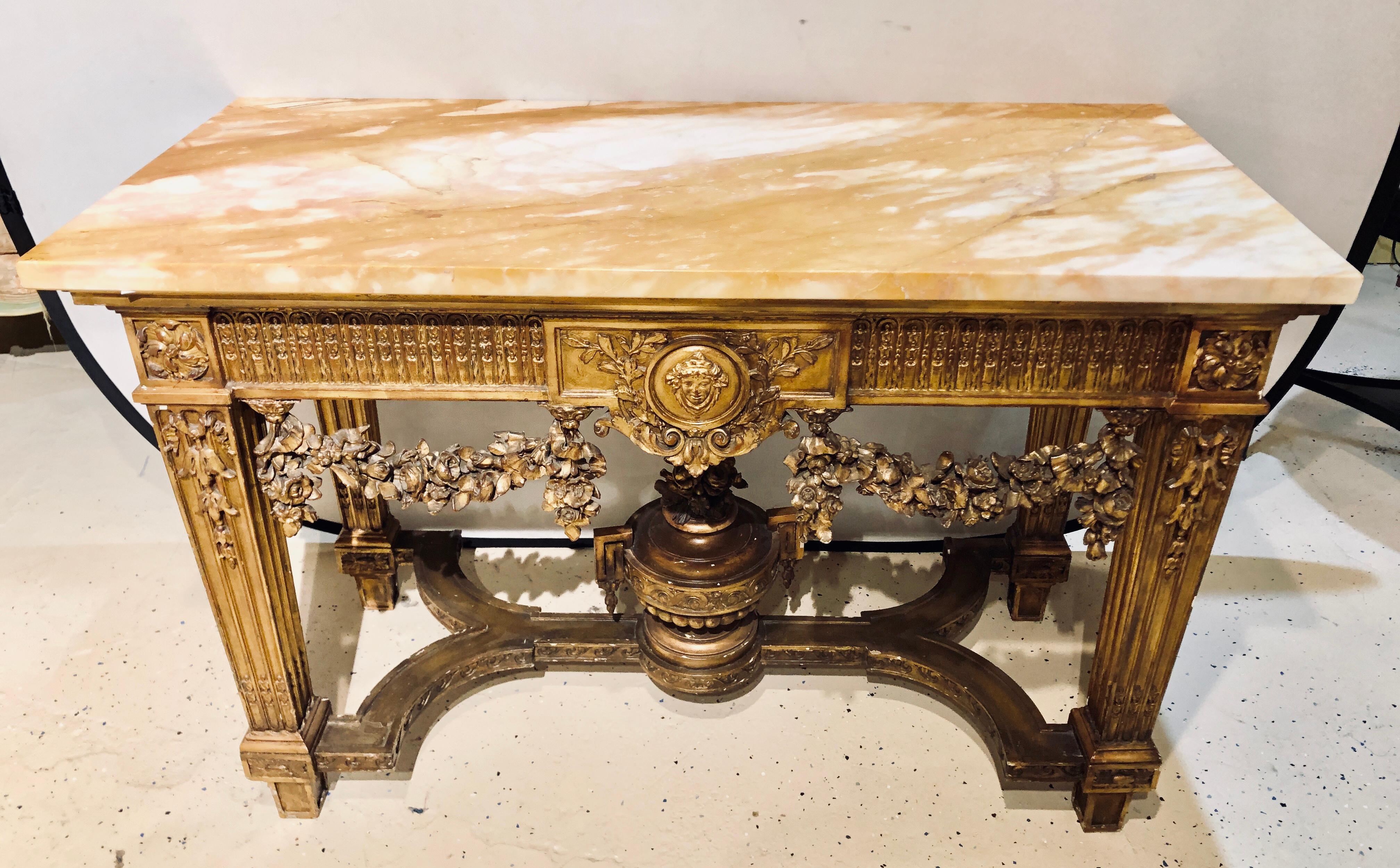 A fine turn of the century Louis XV style giltwood marble-top console table with urn form undercarriage. This fine intricately carved console table depicts the error of grandiose living at its peak. In a gilt worn finish having carved swags of roses