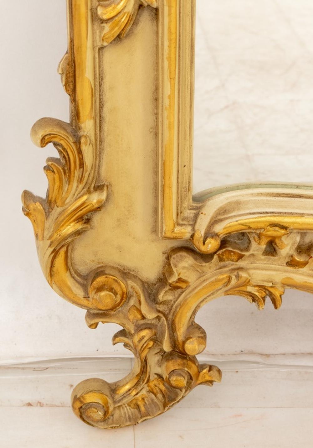 Miroir de style Louis XV en bois doré et peint en crème, le cadre feuillagé avec des pieds à volutes entourant une plaque de miroir, marqué 