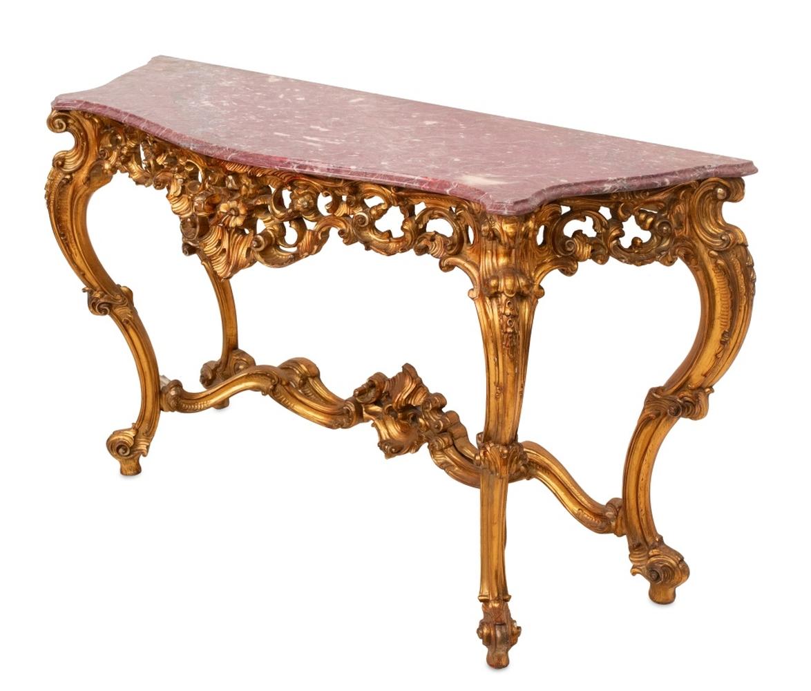 Louis XV Style Giltwood and Pink Marble Serpentine Shaped Console Table, 20th century, the molded top above a pierced frieze centered by flowers, on scrolled cabriole legs, joined by stretchers. 36