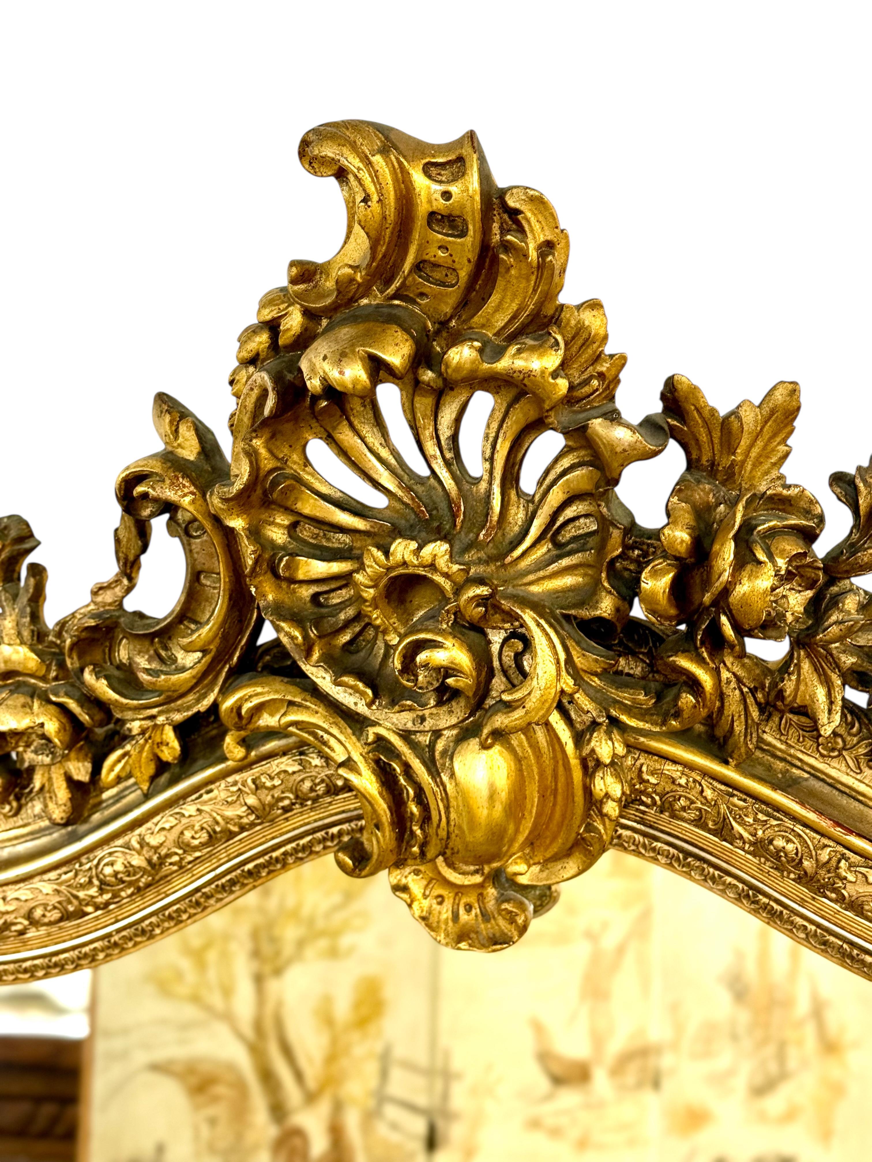 This exquisite French mirror dates to the late 19th century and is a superb example of Rococo revival craftsmanship. The frame is richly decorated with hand-carved floral and acanthus motifs, all meticulously highlighted with original gold leaf