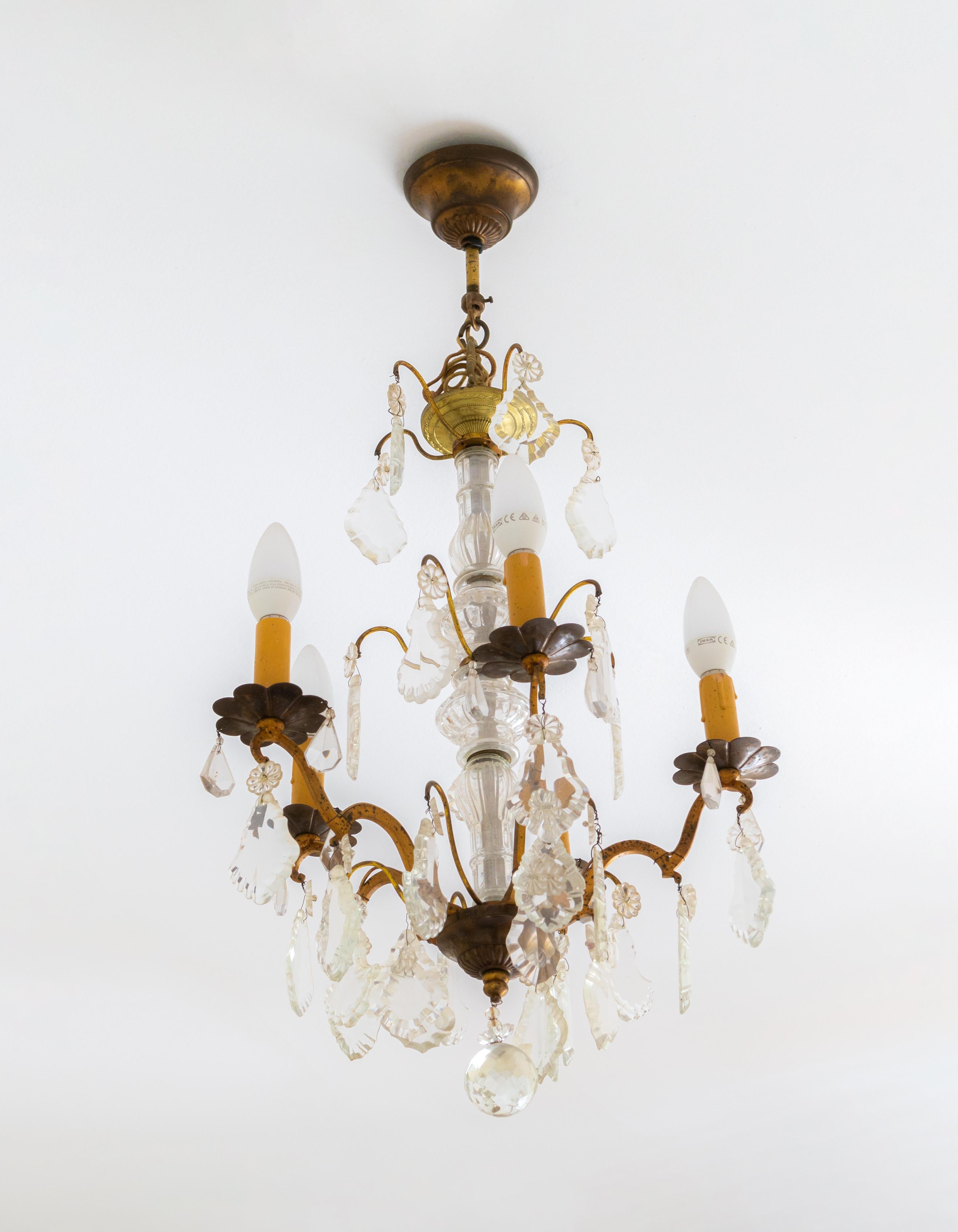 Araña de estilo Luis XV con estructura de cinco ( 5 ) brazos de bronce dorado y cobre con elementos de cristal. 

El tallo central está formado por elementos de vidrio finamente tallados, con gotas decorativas de cristal transparente que reflejan la