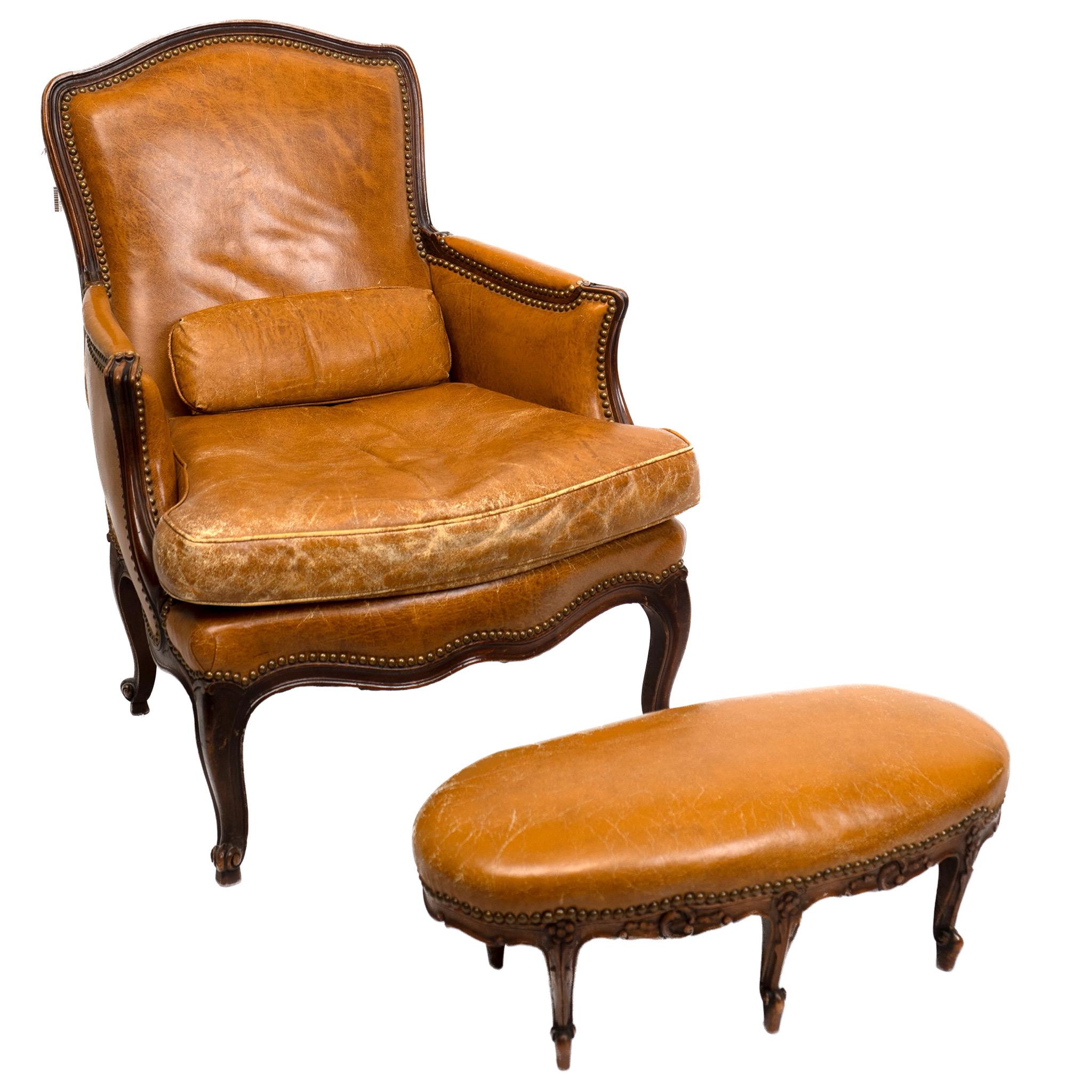 A late 19th century walnut bergere with shaped leather-padded back above a broad cushion seat raised on carved cabriole legs, the tabouret of oval form raised on similarly worked legs, both pieces detailed with upholstery finishing tacks.