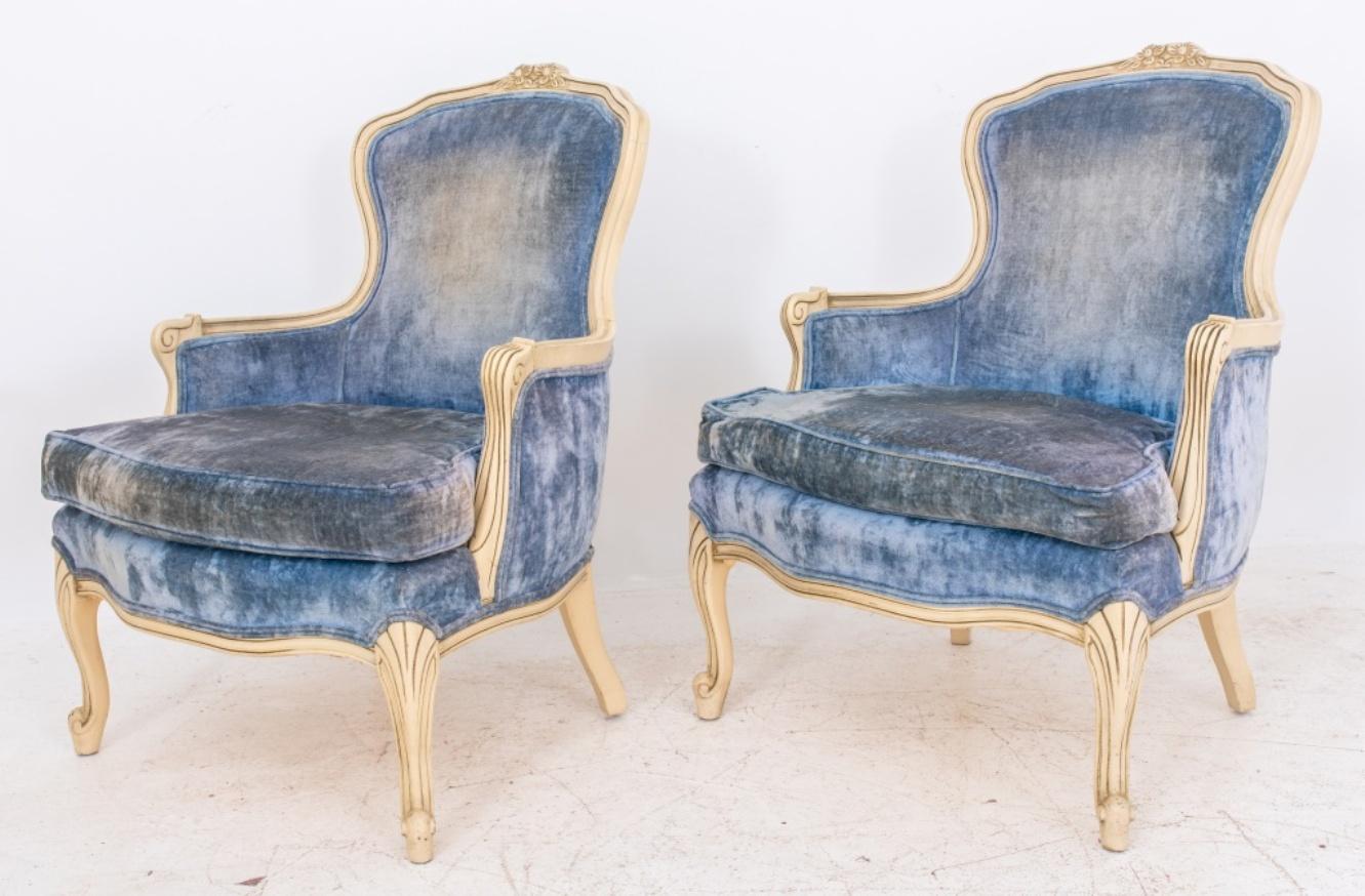Louis XV style bergeres or arm chairs, carved lacquered wood with floral patterns on back, and a shaped seat with cushion, upholstered in a light blue velvet, above cabriole legs with scroll feet. 35.5