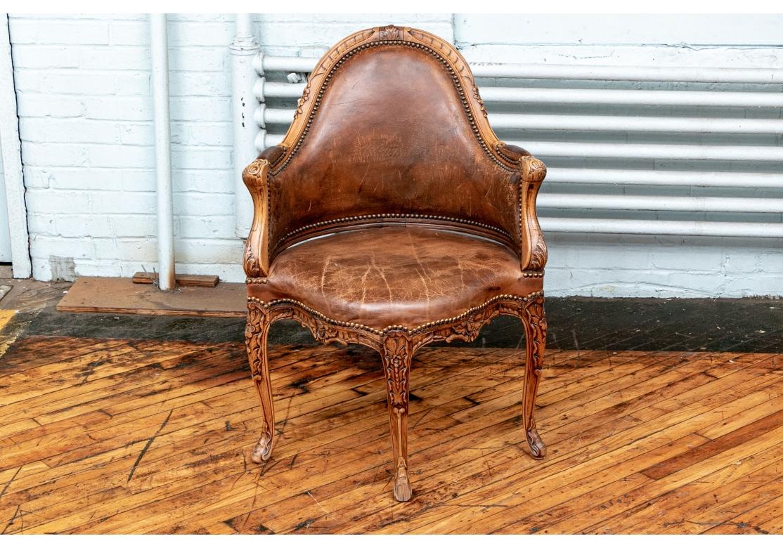 The deep shaped seat is upholstered in brown leather, and its shaped rail mirrors the back and has carved scrolled foliate motifs. Raised on four carved cabriole legs with heavy knees. Brass nail head trim on the leather. 

Measures: height 36 1/2