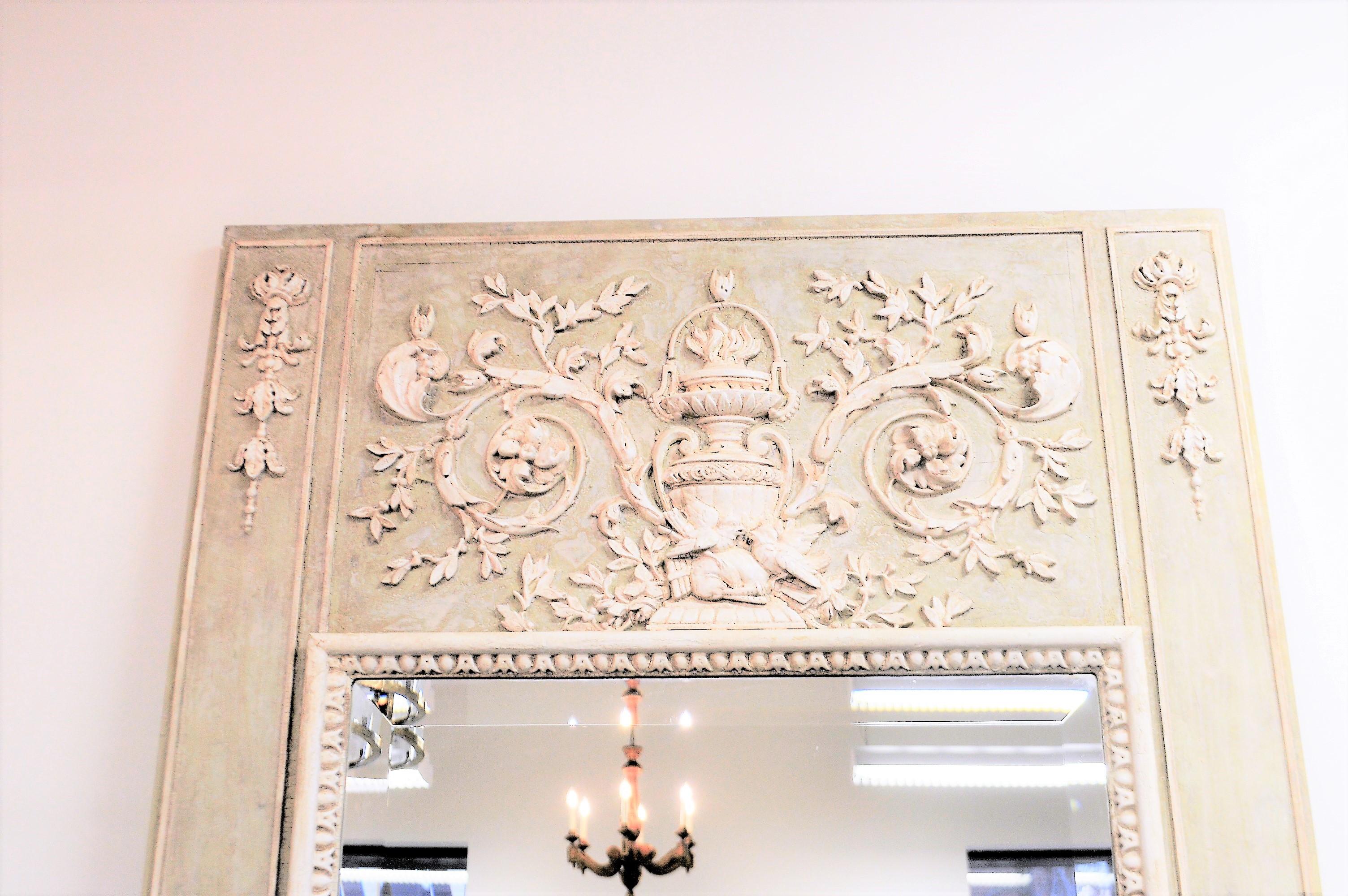 Interesting hand carved details on this light green trumeau mirror. The hand carved details accents have been painted in an antique white. The beveled mirror is new.