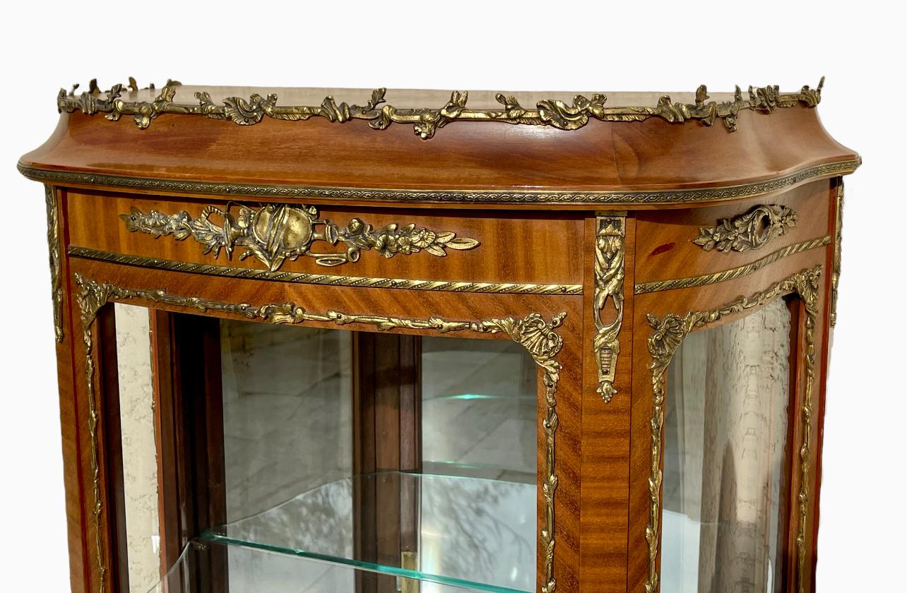Louis XV style mahogany and marquetry display case decorated with bronzes. Circa 1920. It is in good condition, opens with one door and has two glass shelves.

Dimensions
Height 1m42
Width 65cm
Depth 33cm