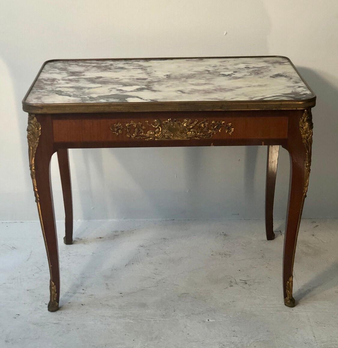 This elegant Louis XV style marble top coffee table is made out of walnut with satinwood inlay. The table has exquisite detailed bronze mounts and a bronze band around the marble top.