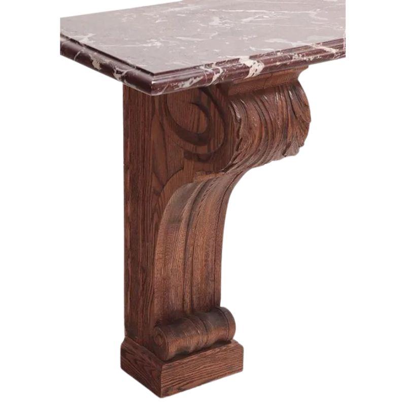 A French rouge marble top console table with a double pedestal oak base. Both pedestals are carved with scroll detail to top and base with acanthus leaf motif at top. Marble is a beautiful shade of red with white veins
