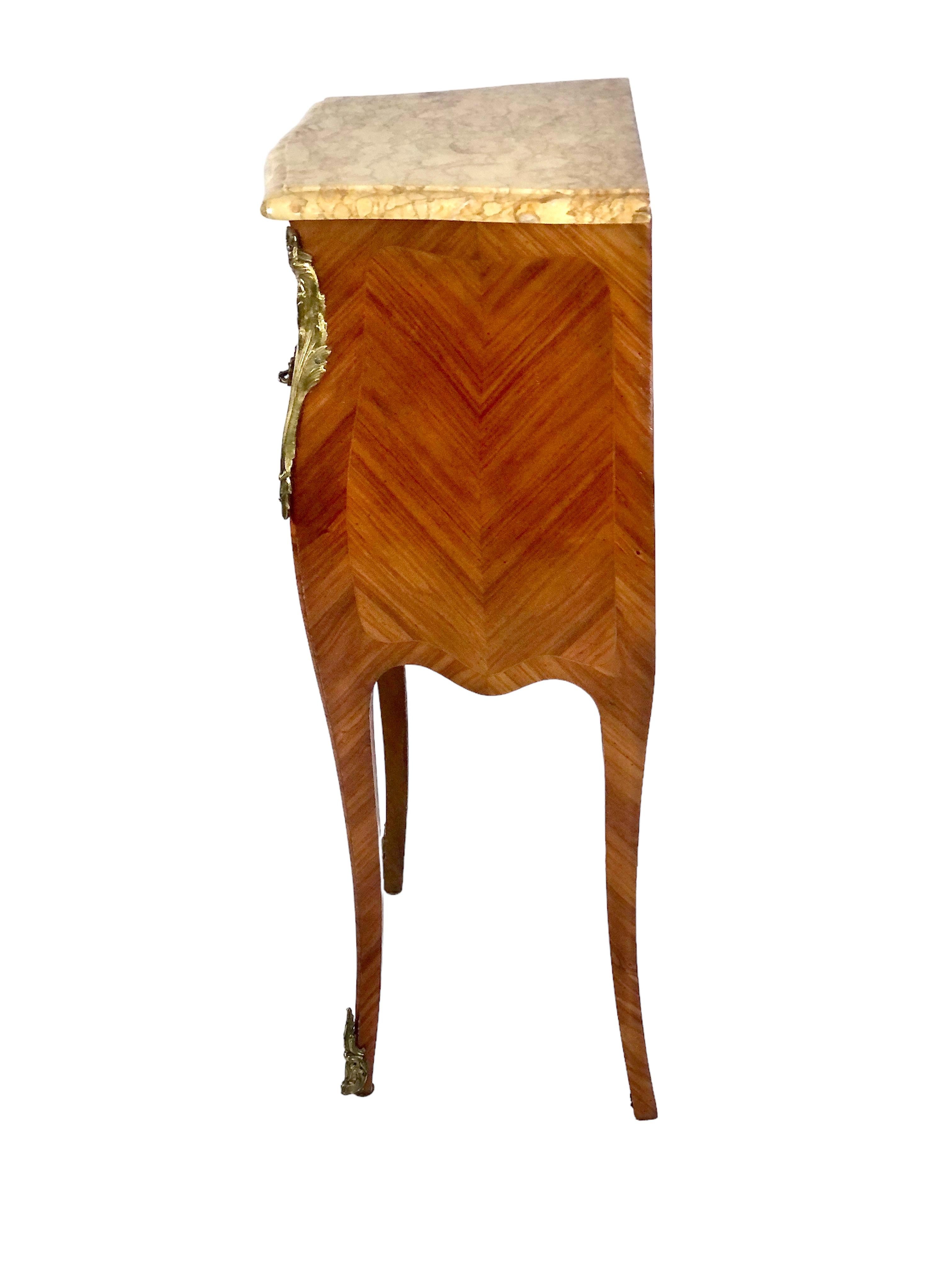 A fine French chevet (bedside table) in Louis XV style marquetry inlaid fruitwood with a marble top. Some lovely gilt bronze handles adorn the three shallow drawers, while the delicate, tapered legs are decorated with matching gilt bronze mounts in