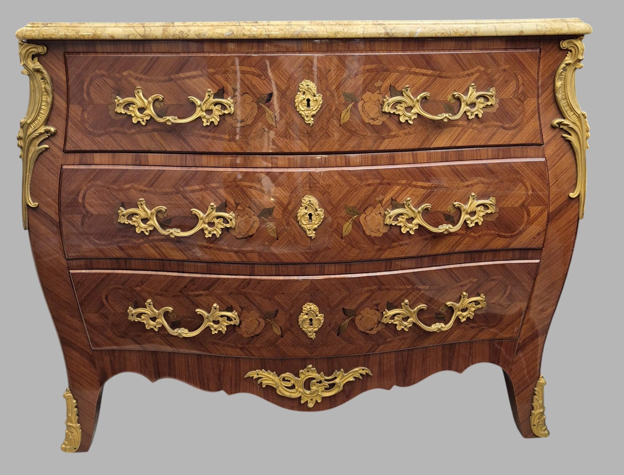 Bellissima commode femminile in stile Luigi XV. Presenta un elegante intarsio di fiori, bronzi dorati e un piano in marmo chiaro. Presenta tre cassetti separati, ciascuno con due maniglie in bronzo dorato.

Un pezzo luminoso, elegante e ben