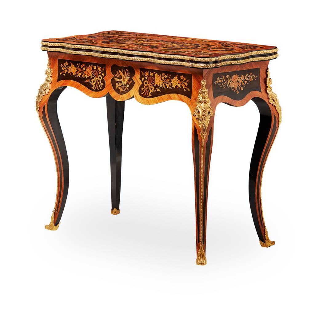 Louis XV style French marquetry and ormolu-mounted fold over card table, circa 1920. The shaped top is profusely inlaid with various woods depicting birds, musical instruments, flowers and scrolls. The outer edge has kingwood banding and the fore