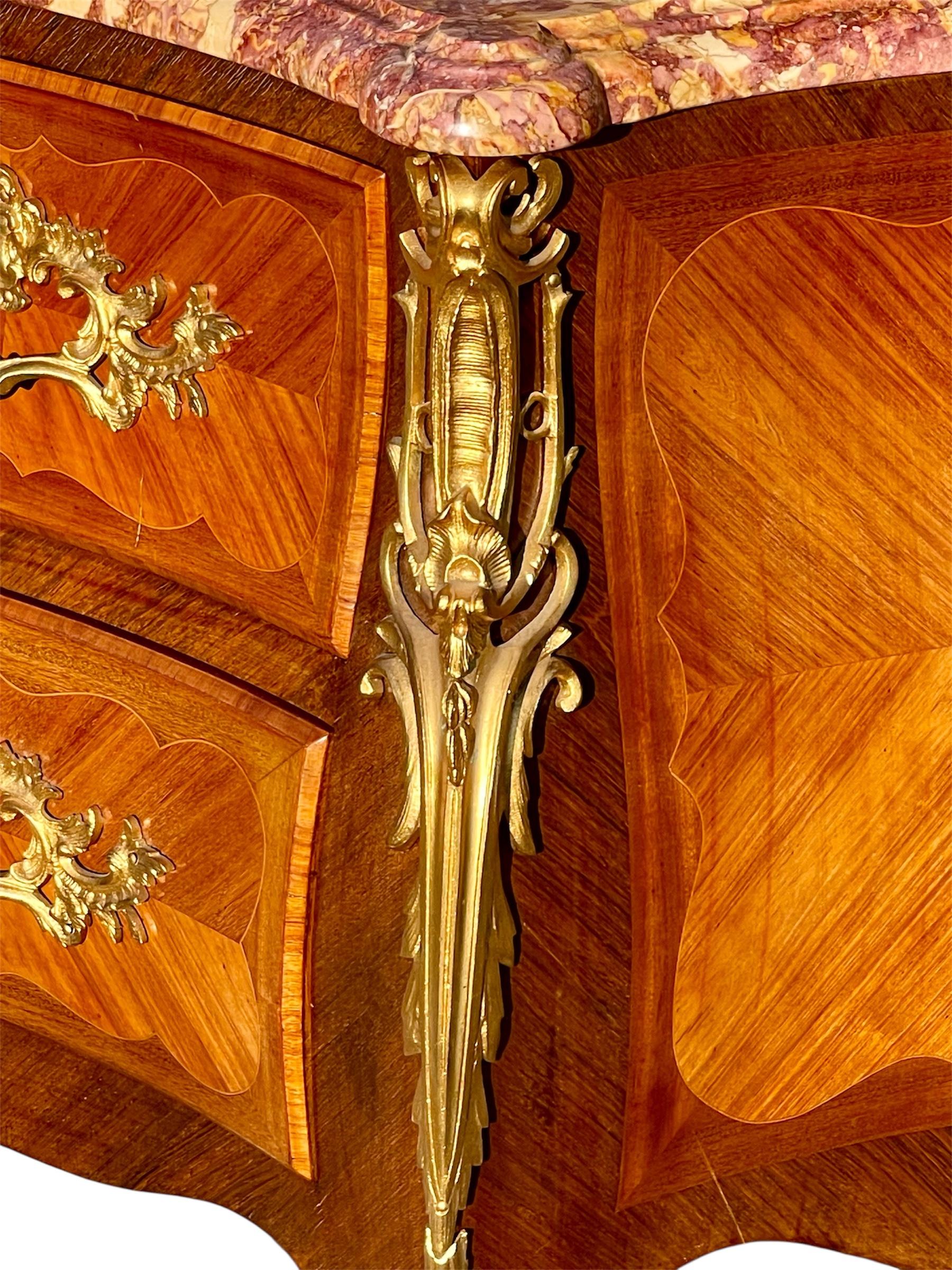 Commode en marqueterie et bronze de style Louis XV datant des années 1930-1940. Elle est à dessus de marbre Brocatelle du Jura. 
 Elle ouvre avec deux petits tiroirs en haut et un grand tiroir en bas.
 Travail français du Faubourg Saint Antoine à