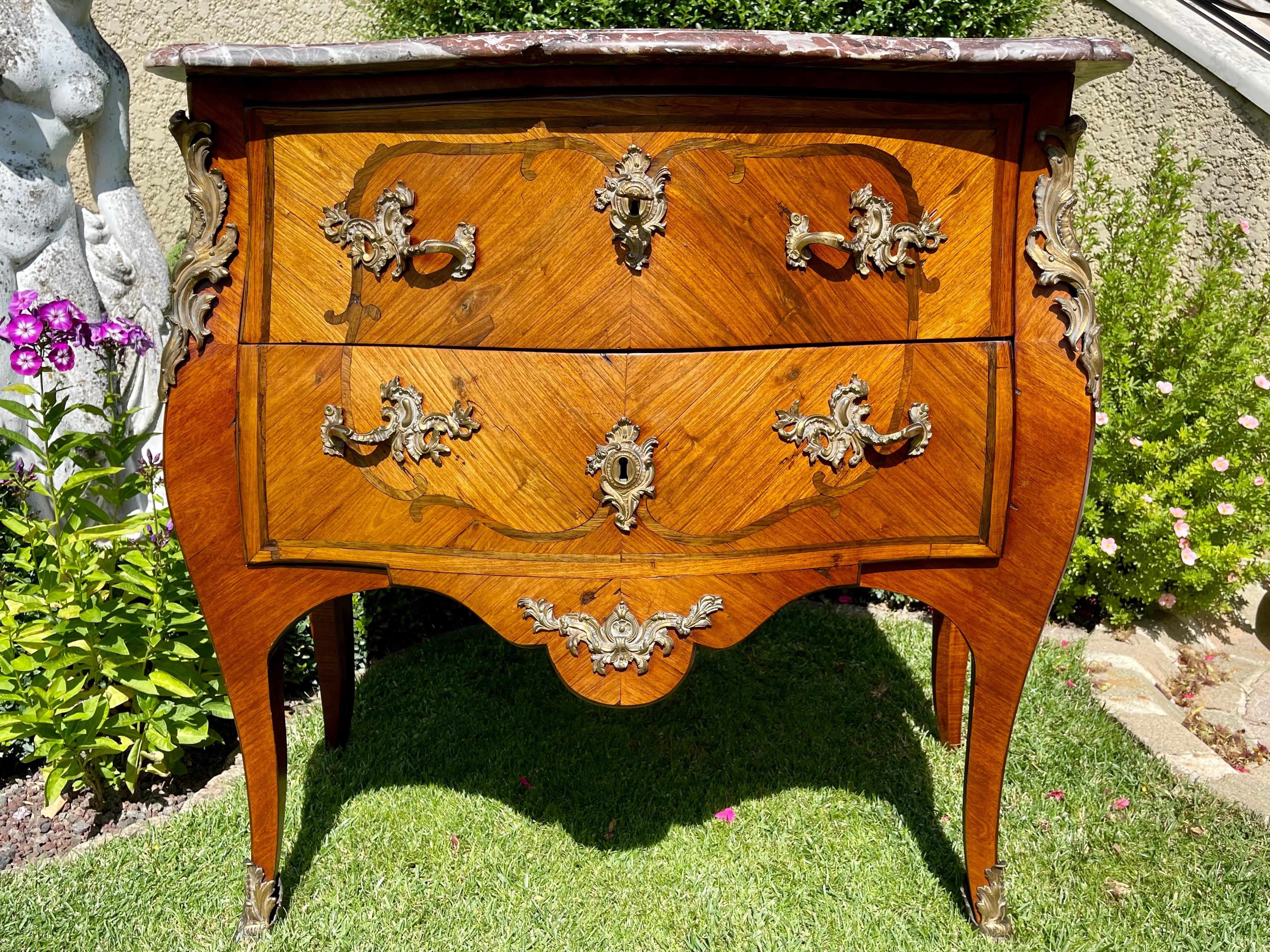 Louis XV commode in marquetry decorated with bronze in good condition. It opens with two drawers and has a marble on top. A small chip on the edge of the marble is to be noted.