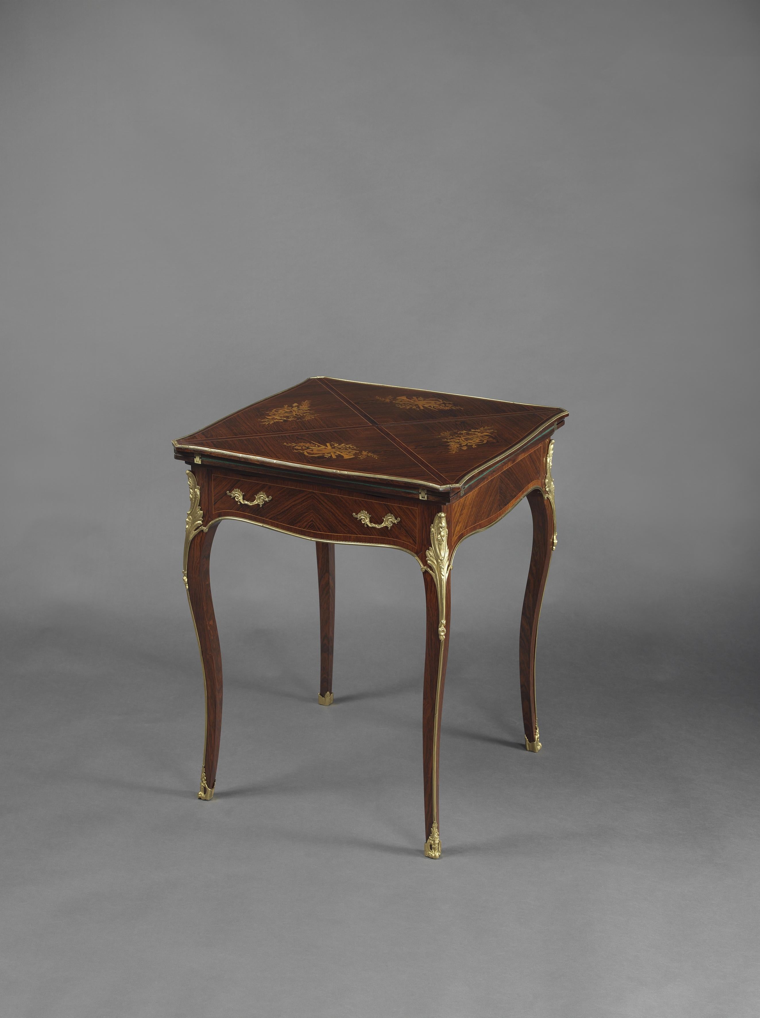 A Louis XV style gilt-bronze mounted marquetry inlaid envelope card table.

French, circa 1890. 

This fine card table has a swivel top, with four 'envelope' panels inlaid with musical trophies opening to a green baize playing surface, the