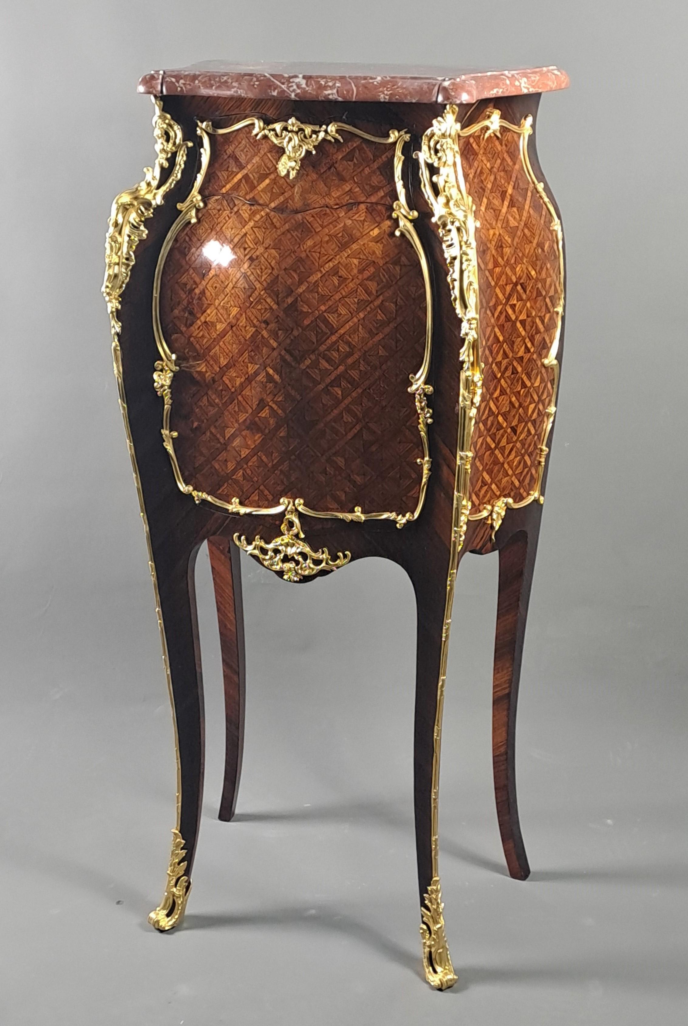 Piccola e graziosa credenza in stile Luigi XV con intarsio a traliccio in legno di violetta e cornici in palissandro di Rio, ricchi ornamenti in bronzo dorato finemente cesellato e piano in marmo reale belga modellato a becco di corbino.
Aprendo un