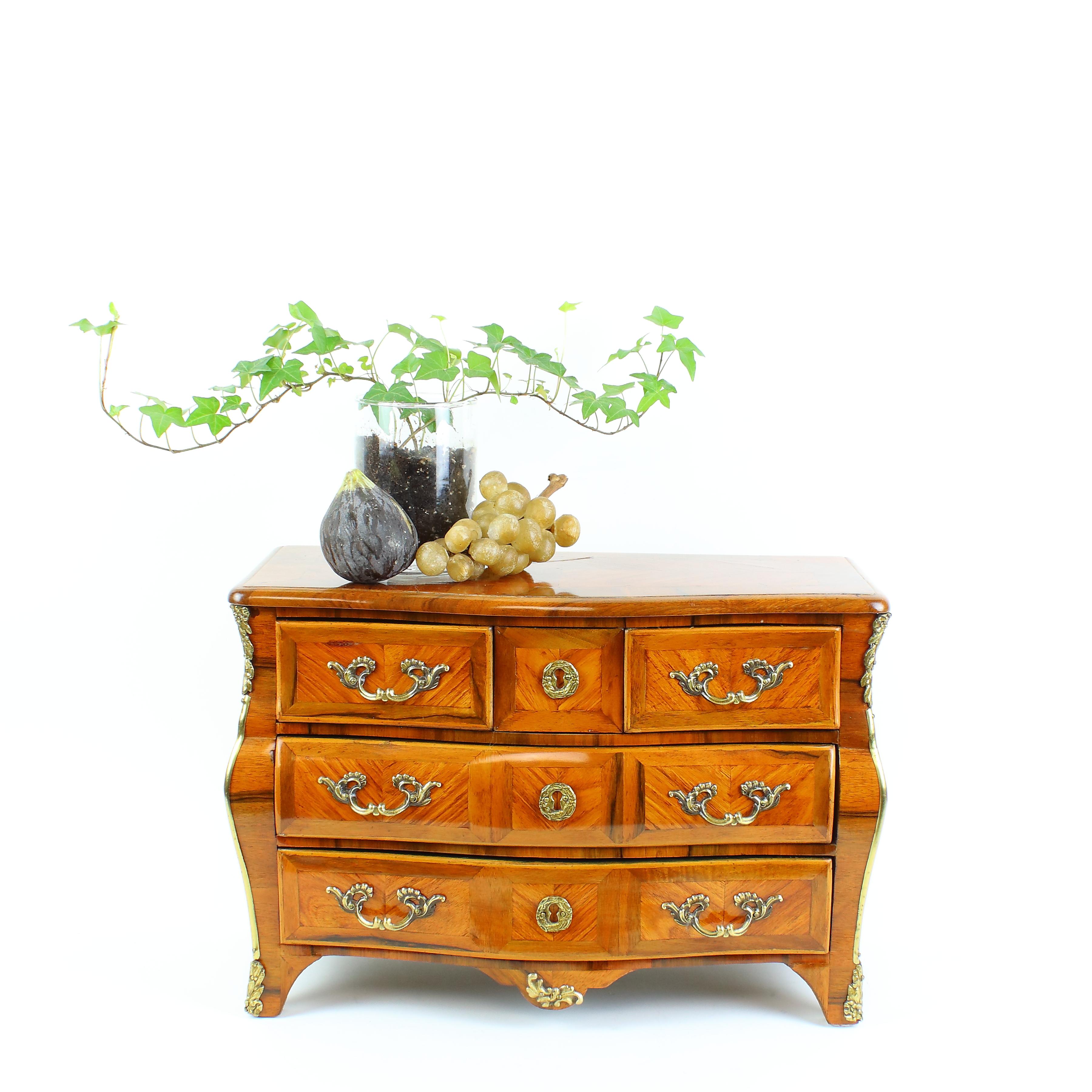 Louis XV style miniature chest of drawers or commode à la Parisienne

A Louis XV style walnut marquetry commode or chest of drawers of tomb-shaped form, the serpentine top echoed by the serpentine front apron, with two large drawers below two