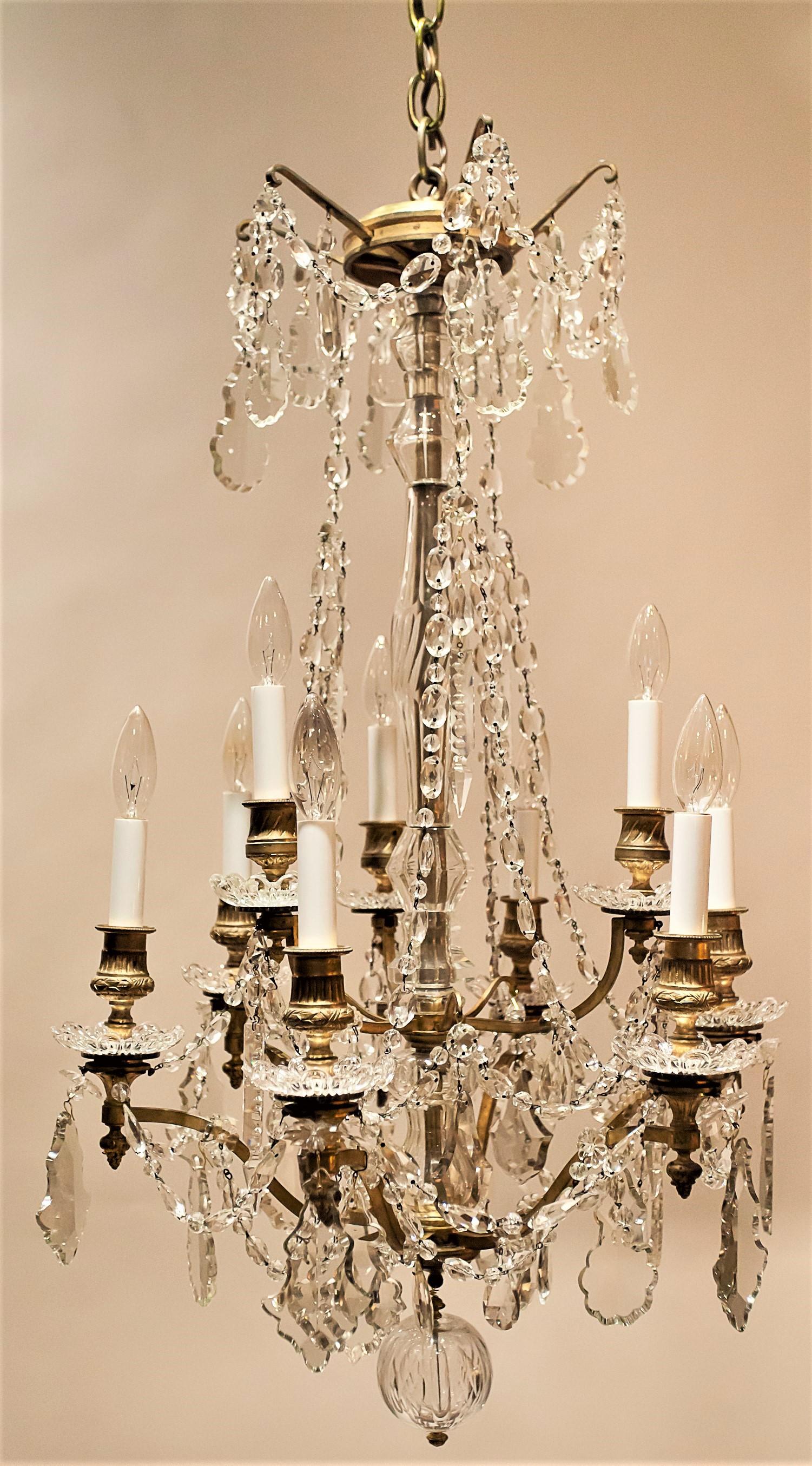 This excellent copy of an 18th century Rococo chandelier has a hand-cast gilt brass frame and handcut lead crystal prisms. The stem is hand blown and cut glass. The crystal trim includes florets, coffins, rosettes, ovals, pears and tear drops.