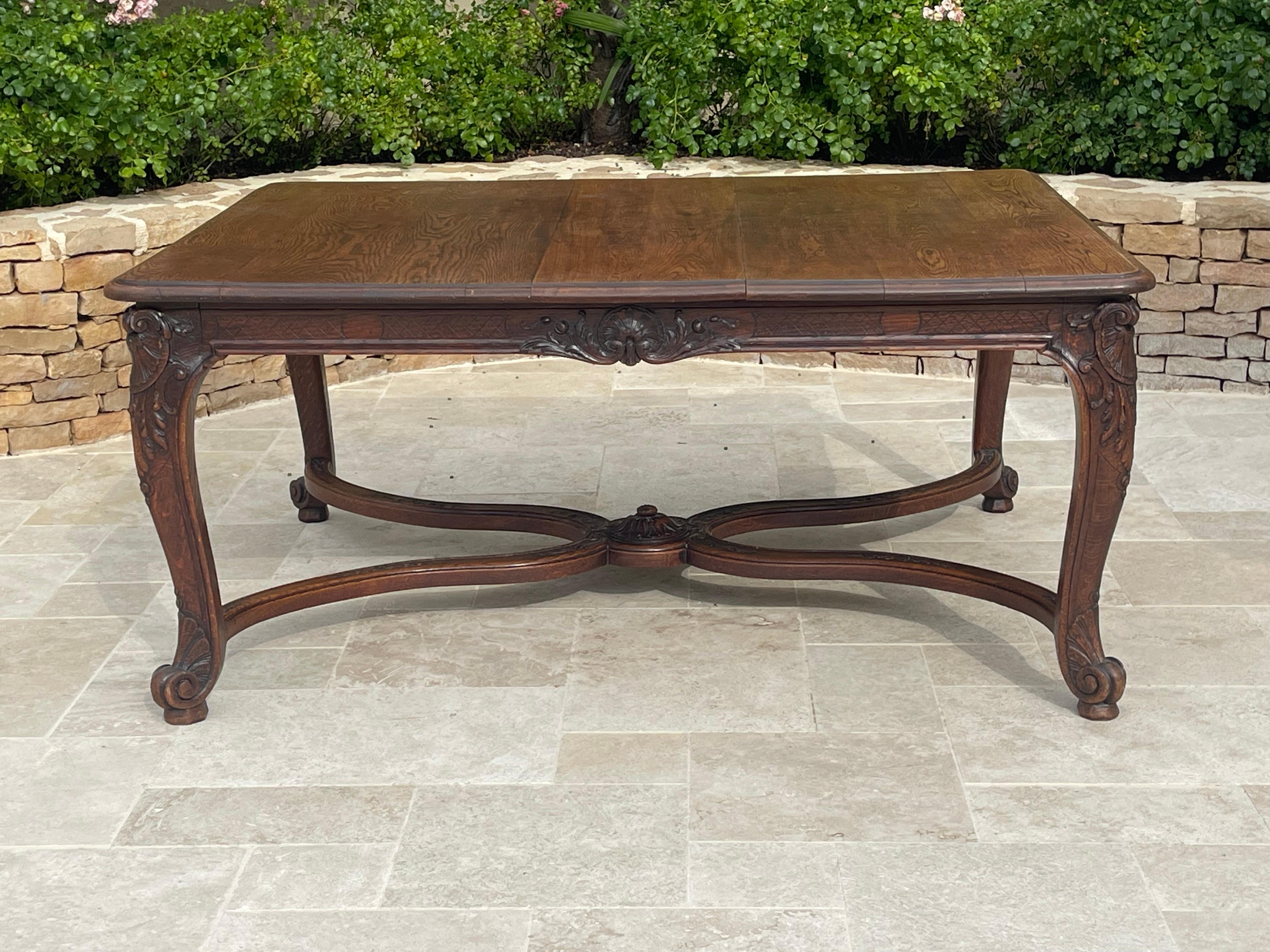 Bonita mesa de comedor de roble macizo, moldeada y esculpida con cuatro patas arqueadas Luis XV terminadas en una voluta en forma de caracol. Los 4 pies están unidos por un separador. Esta mesa admite 2 extensiones para aumentar el número de