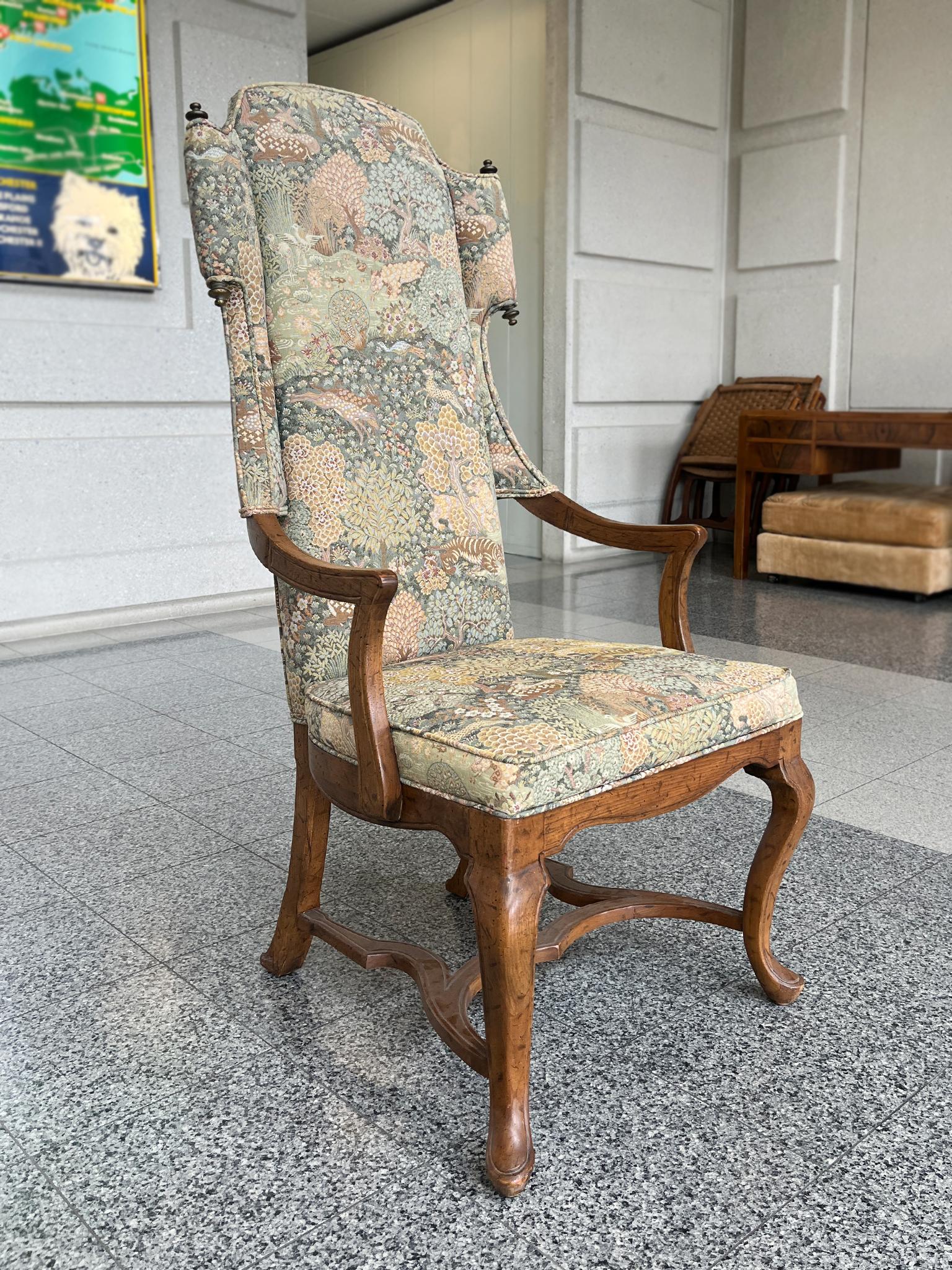 Este sillón orejero vintage del siglo XX está fabricado en estilo Luis XV. Consta de un armazón de madera de roble y una tapicería de trama ricamente estampada. El motivo representa una densa escena boscosa rebosante de plantas y animales.