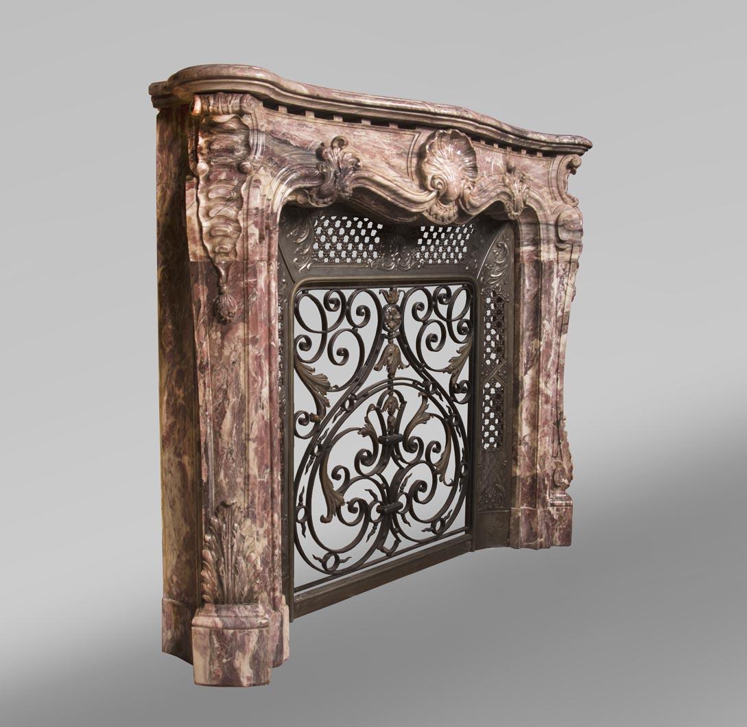 Hand-Carved Louis XV style opulent fireplace sculpted out of Fleur de Pêcher marble For Sale