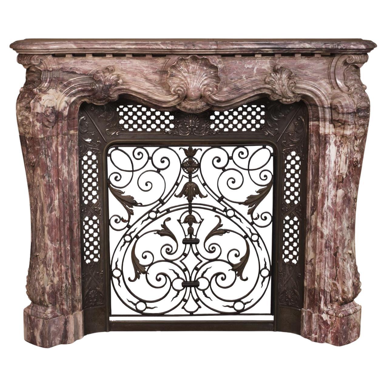 Louis XV style opulent fireplace sculpted out of Fleur de Pêcher marble