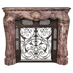 Louis XV style opulent fireplace sculpted out of Fleur de Pêcher marble