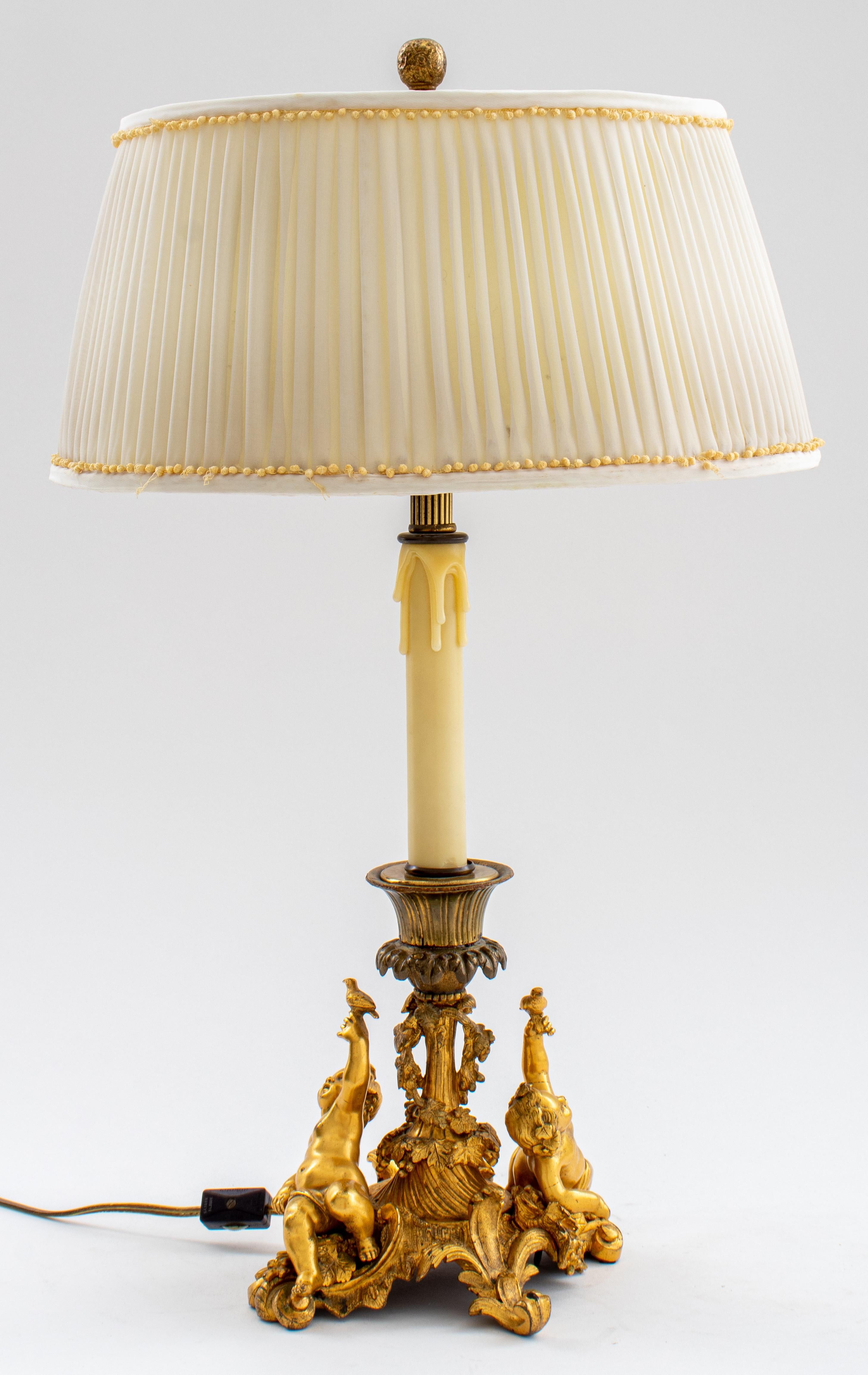 Louis XV Style Ormolu Candlestick Lamp, c. 1900, the ormolu base depicting two putti in the manner of Meissonier atop fruiting rocailles flanking a wreathed column supporting a single light. 22.5