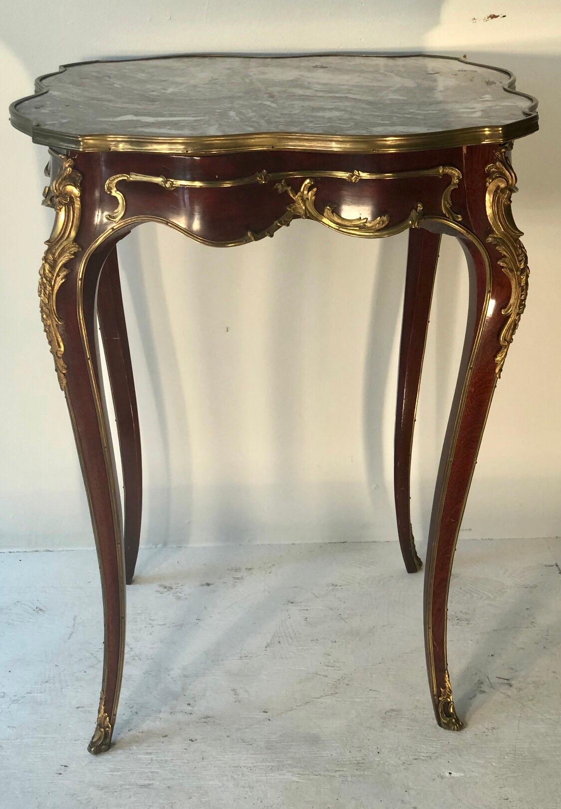 Dieser elegante Beistelltisch mit Marmorplatte im Louis XV-Stil ist mahagonifarben furniert und mit Doré-Bronzebeschlägen versehen, Ende 19. Der Marmoraufsatz befindet sich über einem Bandfries mit Ormolu-Beschlägen. Der Tisch steht auf vier