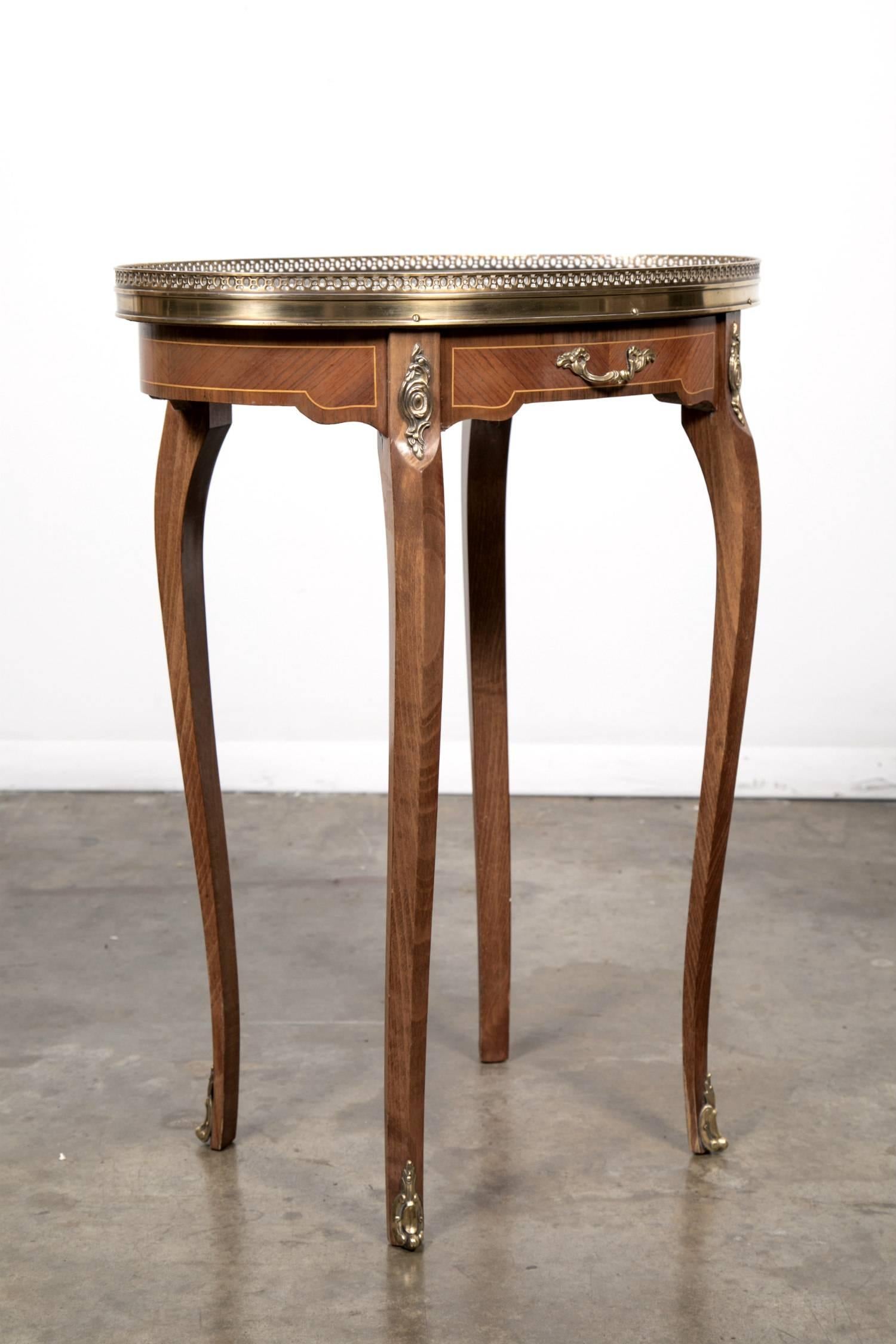 Charming Louis XV style oval kingwood bouillotte table, having a striking marble top surrounded by a pierced gallery. Features a carved apron with inlay, ormolu leg mounts and a single drawer. Raised on graceful cabriole legs ending in bronze sabots.