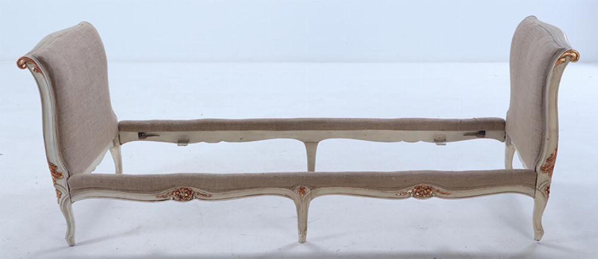 Louis XV style painted and gilt daybed C 1950 having gently curved, upholstered headboard and footboard all supported by a floral and foliate carved frame. Recently reupholstered in a burlap type fabric. Interior dimensions: 73