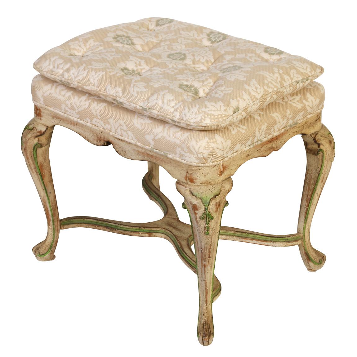 A vintage Louis XV style painted and upholstered small bench.  The graceful cabriole bench legs are painted a distressed cream with green accents and meet with a curved X stretcher.  The seat is upholstered in a neutral, soft tufted fabric.  