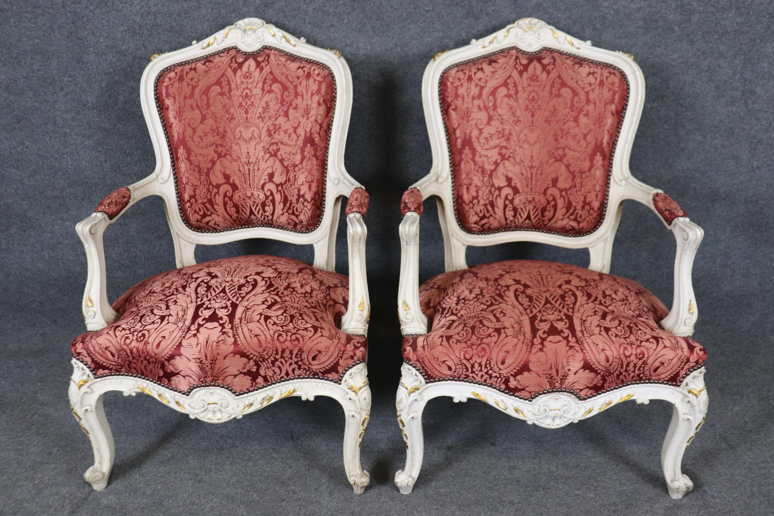 Une des deux paires disponibles séparément.  
Il s'agit d'une superbe paire de fauteuils de style Louis XV peints en craquelé, avec une tapisserie en soie rouge et de subtiles touches de feuilles d'or. Les chaises sont en bon état vintage avec des