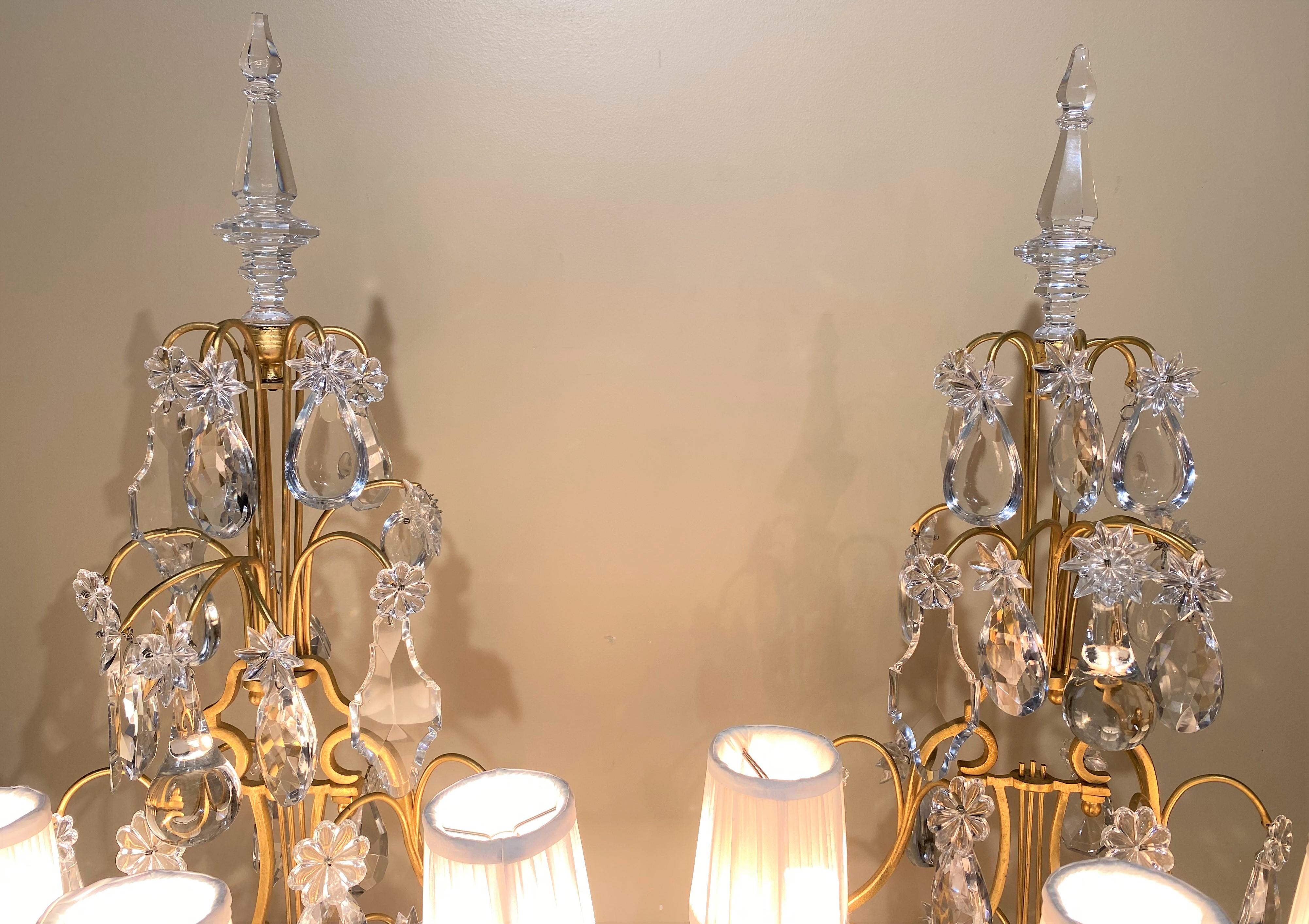 Magnifique paire de garnitures à trois lumières de style Louis XV avec des bases peintes en faux marbre ou en vert malachite, quatre niveaux de prismes en cristal taillé de différentes formes, ainsi que des épis de faîtage en verre en forme de