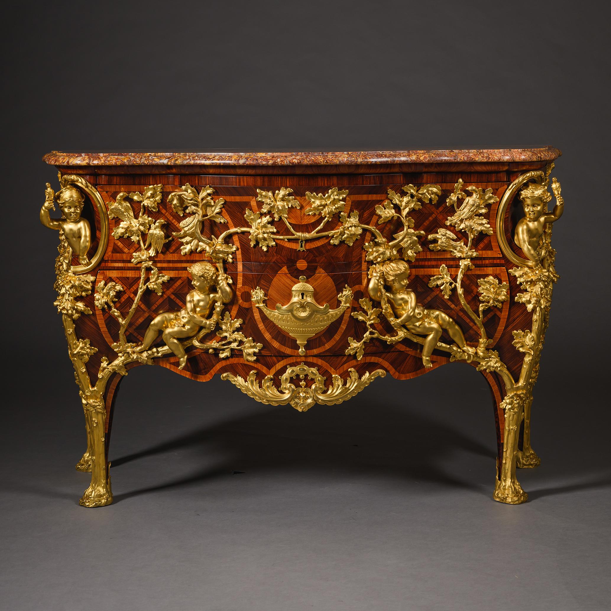 Commodo in parquet in stile Luigi XV riccamente ornato da Charles Cressent, sormontato da un piano in marmo brèche d'Alep a serpentina. Il frontale bombato racchiude due cassetti impiallacciati in legni pregiati con cartigli a nastro e parquet a