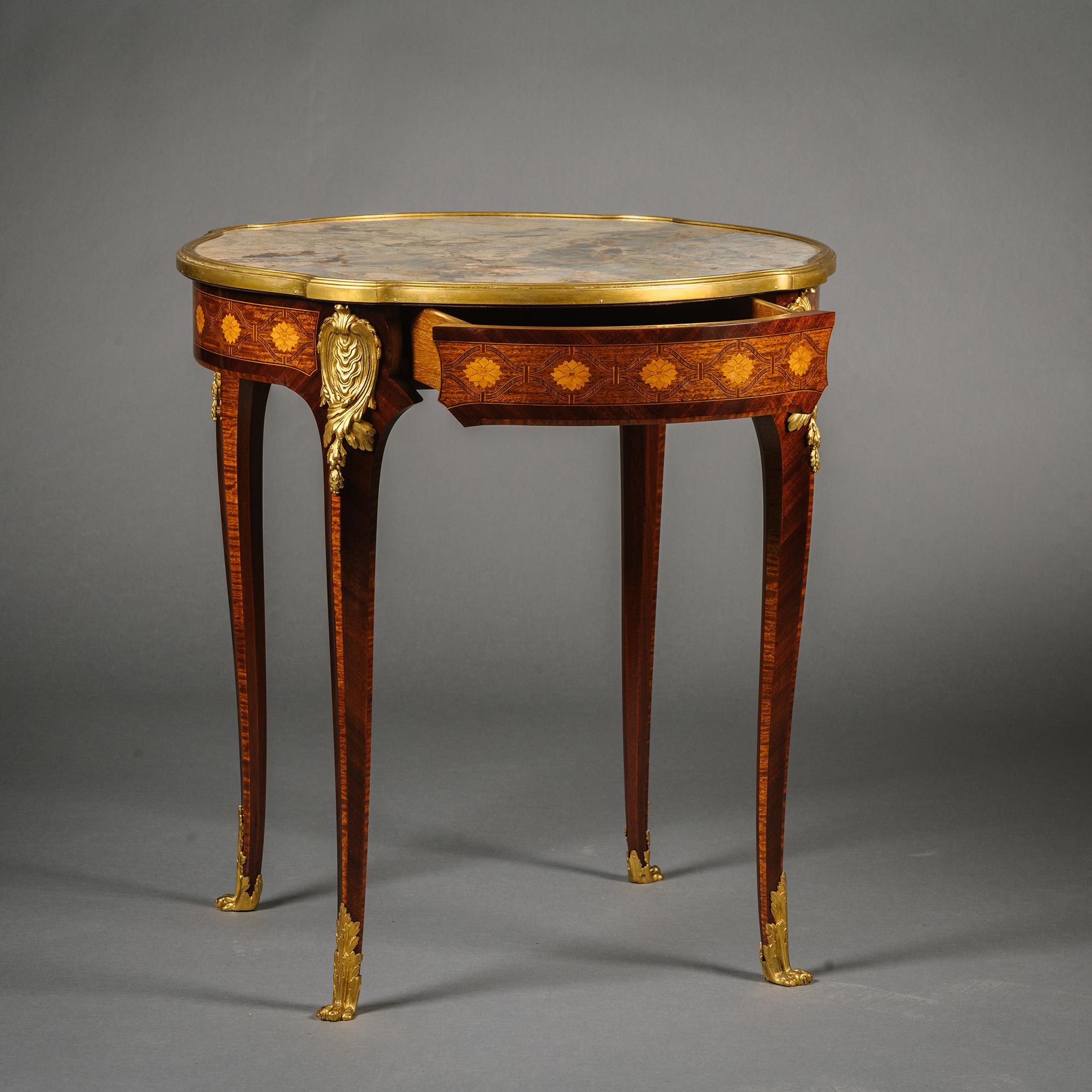 A Louis XV Style Gilt-Bronze Mounted Mahogany and Parquetry Occasional Table.

The Sarrancolin marble top within a gilt-bronze surround. The frieze is decorated with superb parquetry of sunflower-filled interlaced trellis in different precious