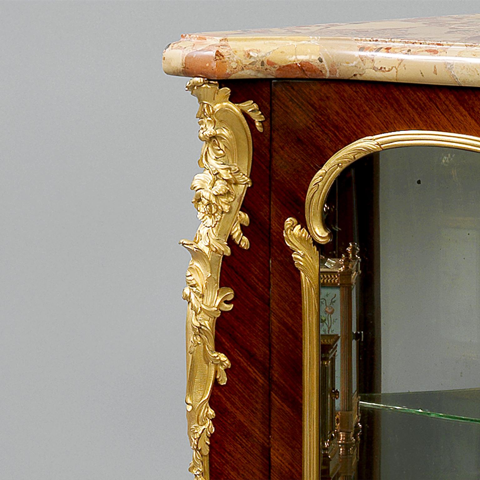 Eine feine, in vergoldeter Bronze gefasste Petit-Eckvitrine im Stil Louis XV von François Linke.

Die vergoldeten Bronzebeschläge sind auf der Rückseite mit 