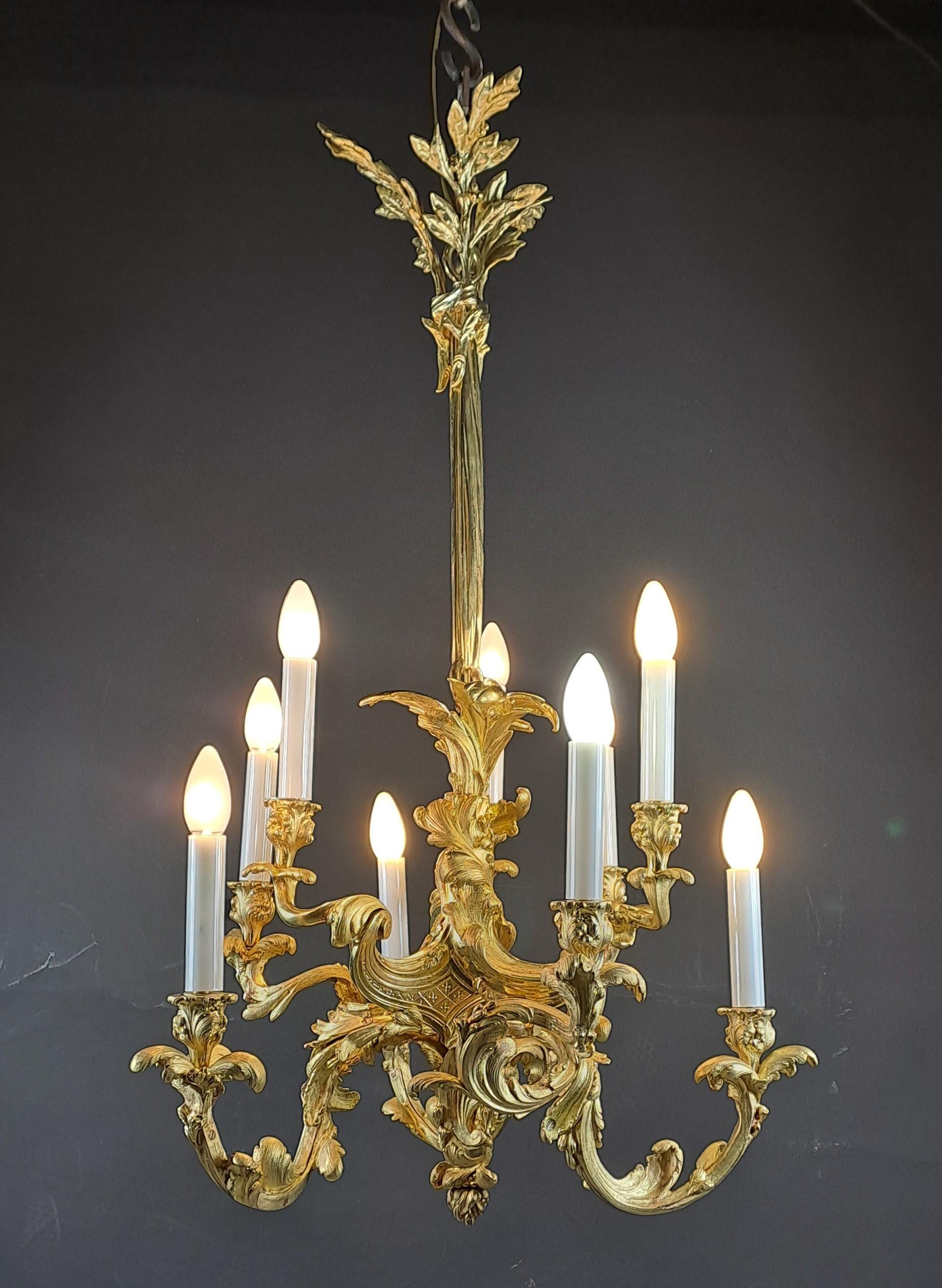 Araña de estilo Luis XV Rocaille de bronce dorado finamente cincelado con una rica y compleja decoración móvil formada por hojas de acanto y volutas entrelazadas.
Brazos de 9 luces acabados con falsas velas de cristal opalino.

Magnífico trabajo en