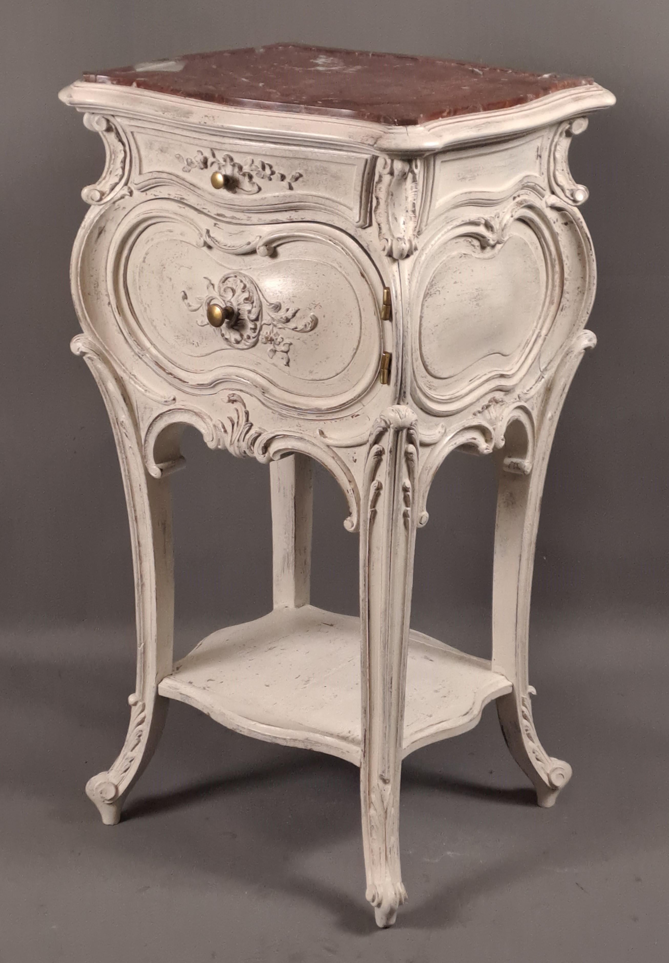 Small side table (originally had a function as a bedside table) curved four sides in richly carved and molded white lacquered walnut, topped with a top of royal red marble from Belgium, opening on the front a drawer and a door, a spacer in the lower