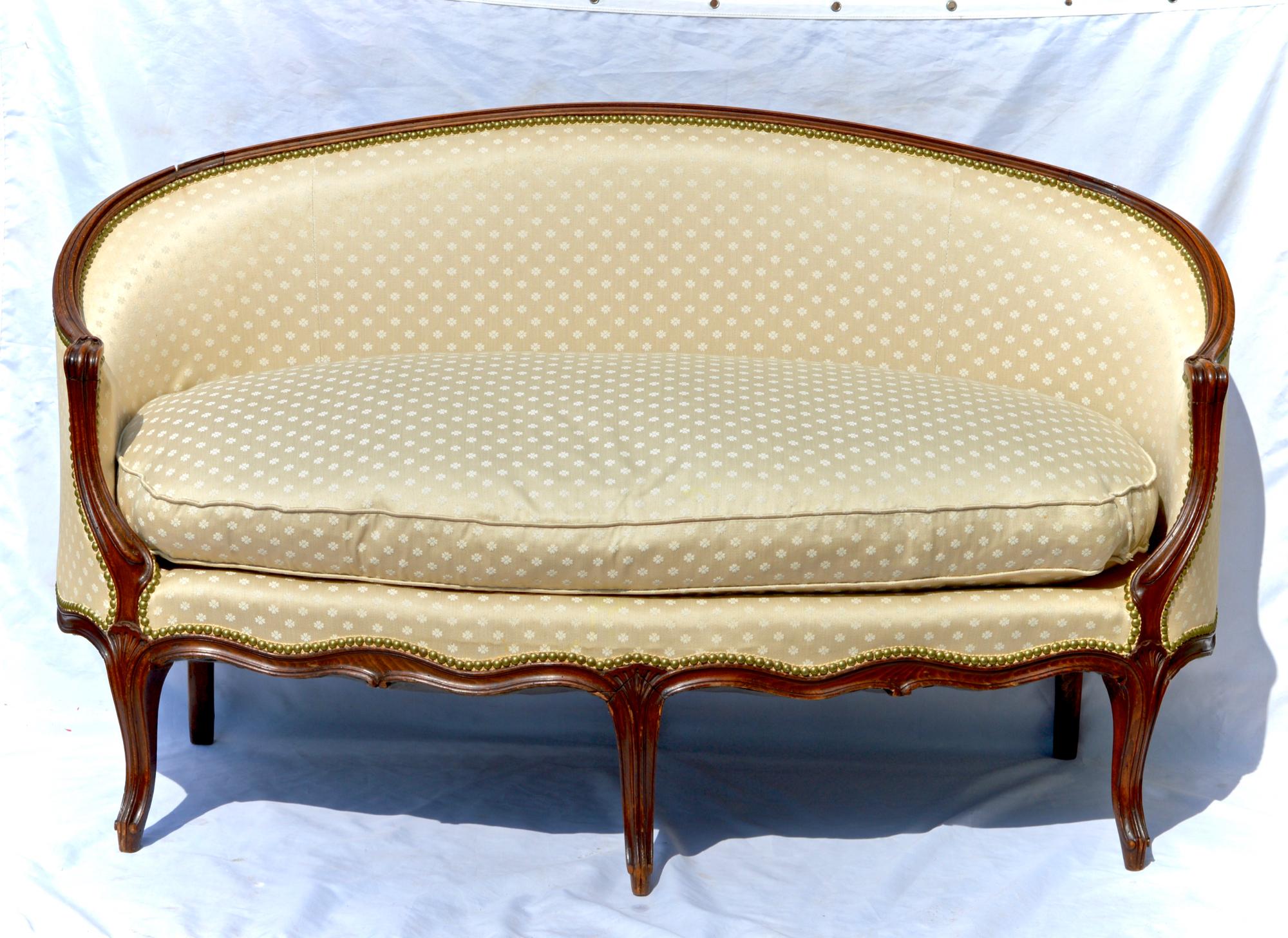 A gorgeous Louis XV style settee having well performed and carved downswept arms, a thick and cozy 100% down cushion and a lustrous patina throughout the pine and walnut frame, circa 1900, the loveseat will add warmth and antique character wherever