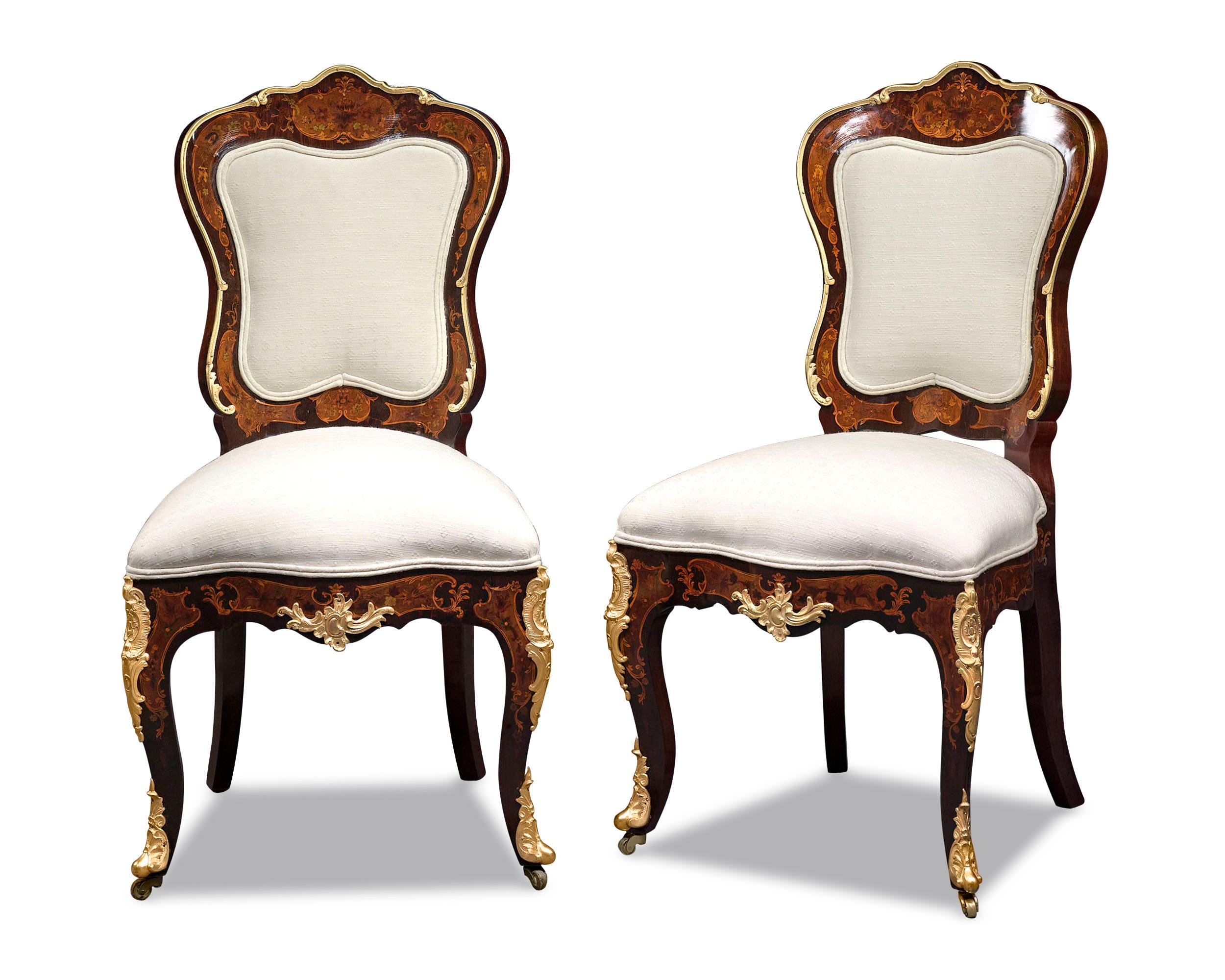 The elegant pair of Louis XV-style side chairs exhibits exceptional artistry. Graceful and feminine lines inform this well-balanced design, from the serpentine backs and seats to the gently curved cabriole legs. This well-balanced design is