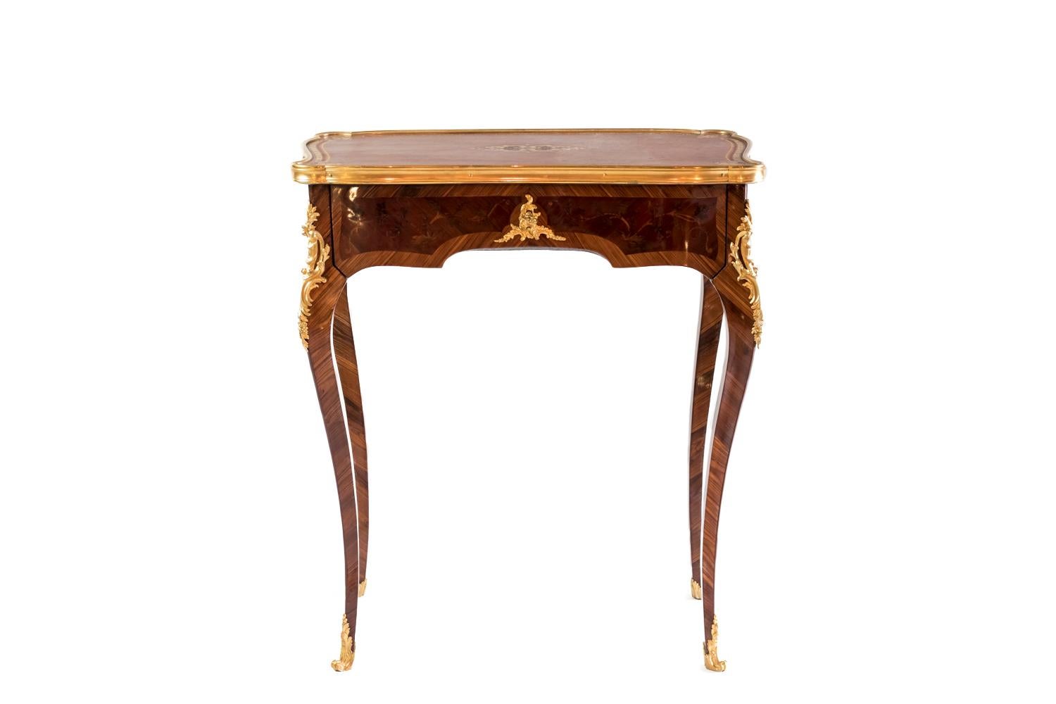 Louis XV style small table in marquetry and gilt bronze standing on four cabriole legs and opening by a drawer. Scalloped apron adorned with a frisage decor and marquetry cartouches with foliage scrolls decoration. Scalloped tray covered with cognac