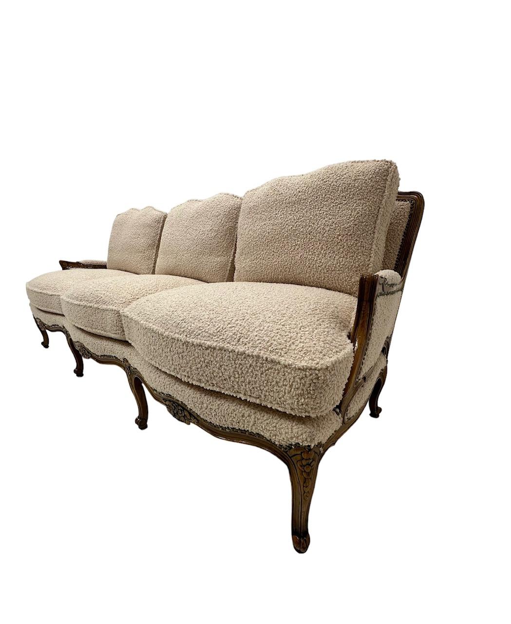 Dieses Sofa im Stil Ludwigs XV. zeugt von der Opulenz und Kreativität der dynastischen französischen Monarchie. Das vollständig restaurierte Sofa ist mit einem ebenso luxuriösen, muschelweißen italienischen Bouclé bezogen. Die äußerst bequemen