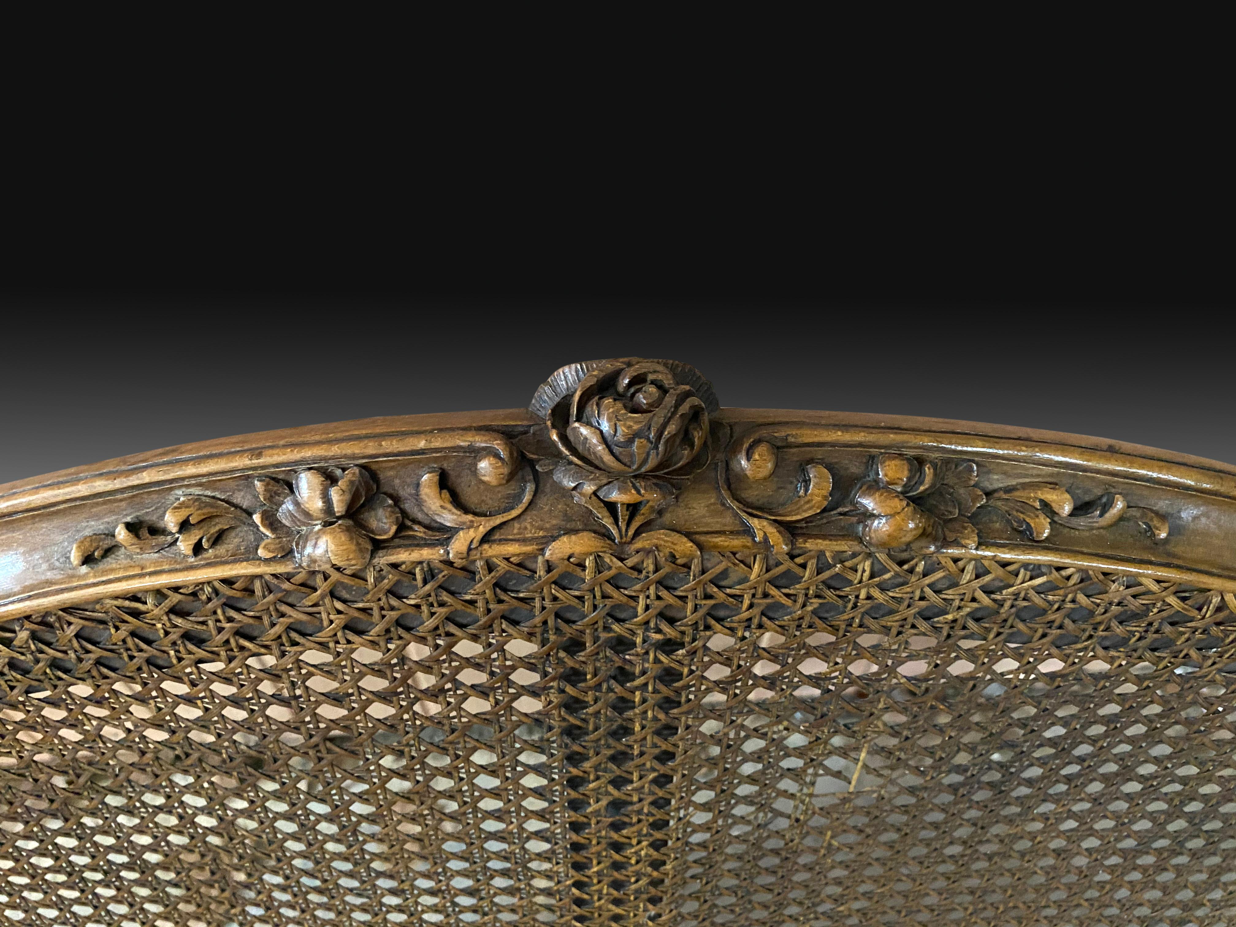Louis XV style mesh sofa. Walnut wood, 19th century. 
Multi-seater sofa with seat and high back with grille and wooden frame decorated with fine carvings of plant and architectural themes. The French influence is notable in the piece (carvings,
