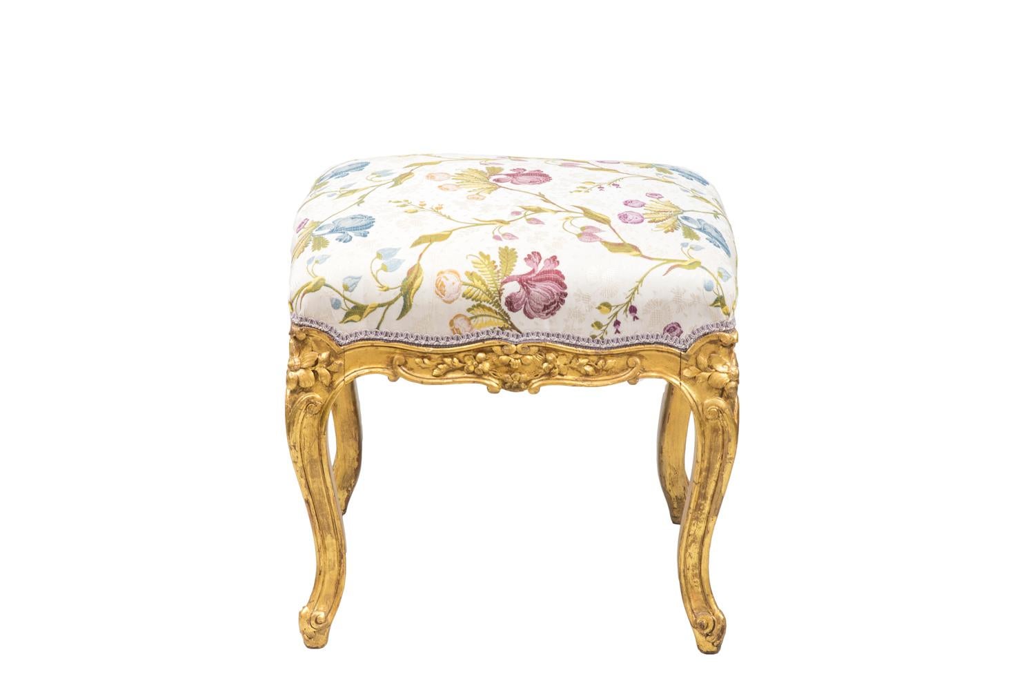 Louis XV style stool in giltwood standing on four cabriole legs finished by scrolls. Scalloped apron with a decor of flowers.
Seat covered by a cream background fabric decorated with blue, pink and yellow flowers.

Work realized circa 1880.