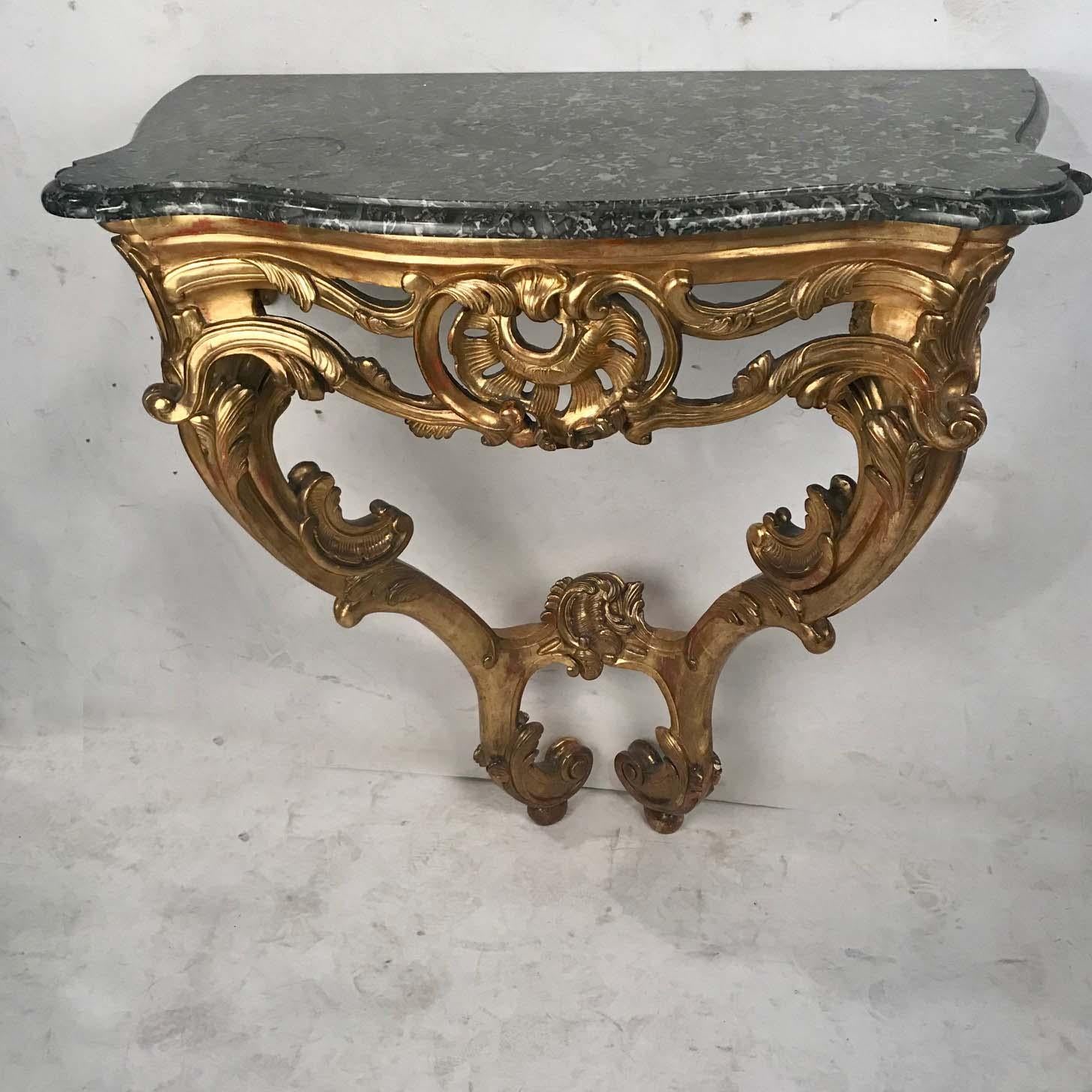 A Louis XV style giltwood console table on two elaborately carved  supports, with well-carved leaf and scroll decoration; the curving and sinuous acanthus motif adds a lightness and movement.
Surmounted by an eared and beveled Gris Saint-Anne marble