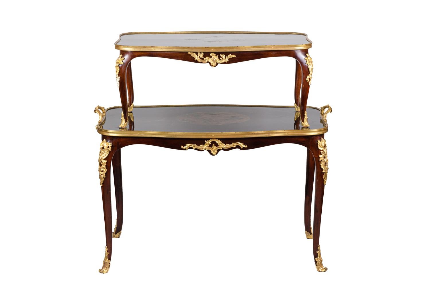 Louis XV style tea table in mahogany with two overlapped scalloped trays, each standing on four cabriole legs. Removable upper tray.
Lacquer decor with a black background and gilt Chinese motifs figuring three circles decorated with a cherry tree,