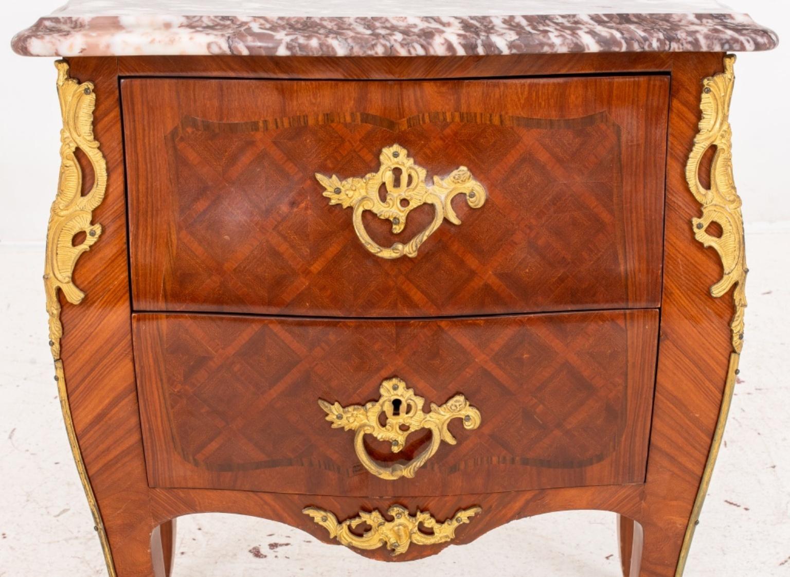 Louis XV style two drawer petite commode or chest, with molded shaped rectangular Breche Violette marble top above two drawers, the front and sides with kingwood parquetry, the chest with ormolu pulls, chutes and sabots. 

Dimensions: 28.5