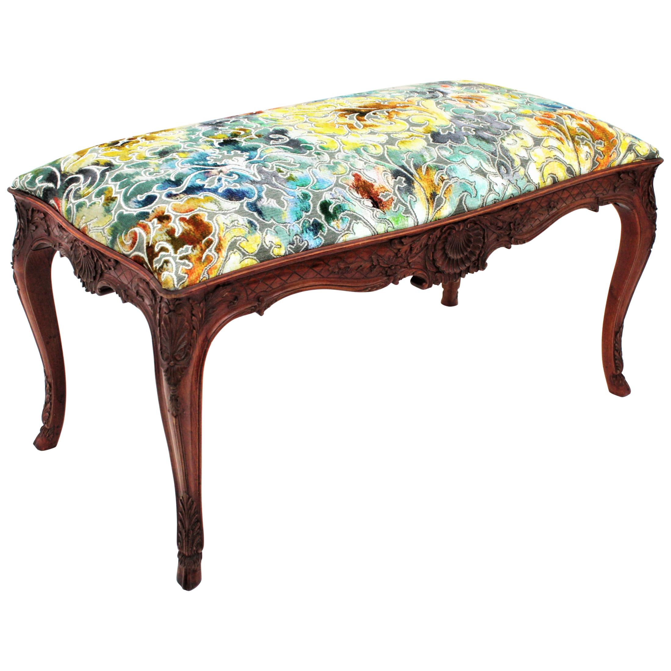 Finely hand carved Louis XV style walnut bench with colorful velvet upholstery, France, 1920s-1930s.
This stylish banquette stands up on graceful cabriole shaped legs with hoof feet endings. It is adorned overall with rocaille, foliate motifs and
